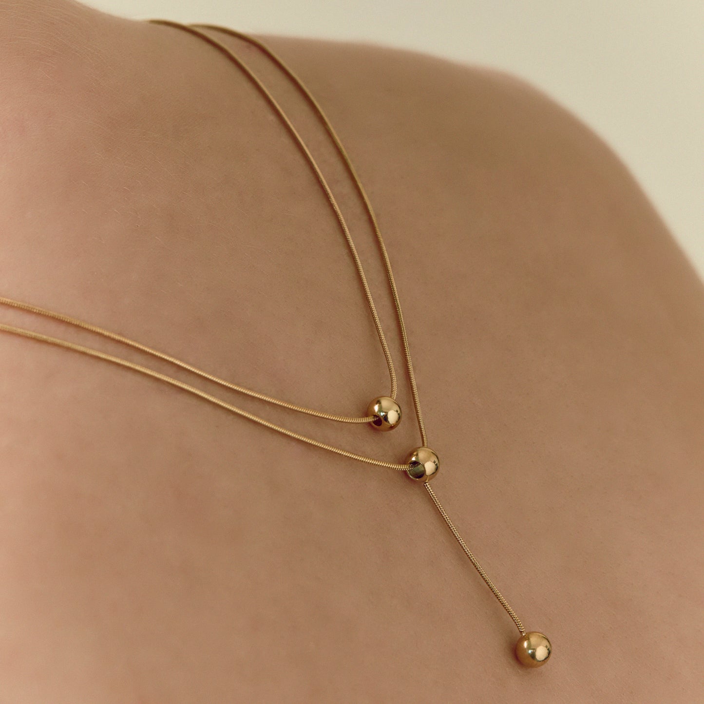 Double-strand 18K gold plated necklace with layered chains and polished ball pendants, delicate and modern for everyday or statement wear.