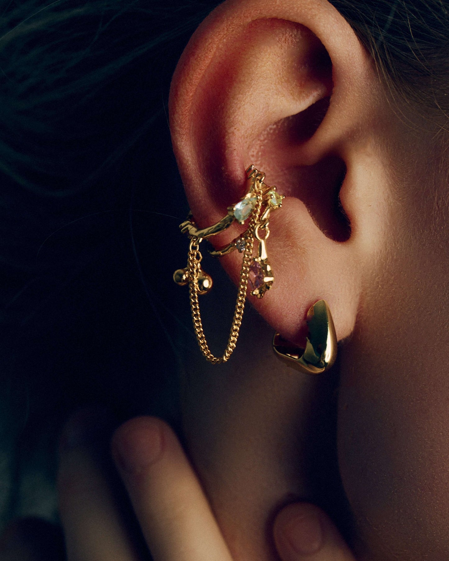 Gold and silver ear cuffs with dangling chains, charms, and colorful cubic zirconia stones. Non-pierced adjustable cartilage cuffs featuring teardrop and square-cut gems for a bold, playful, and trendy statement look.