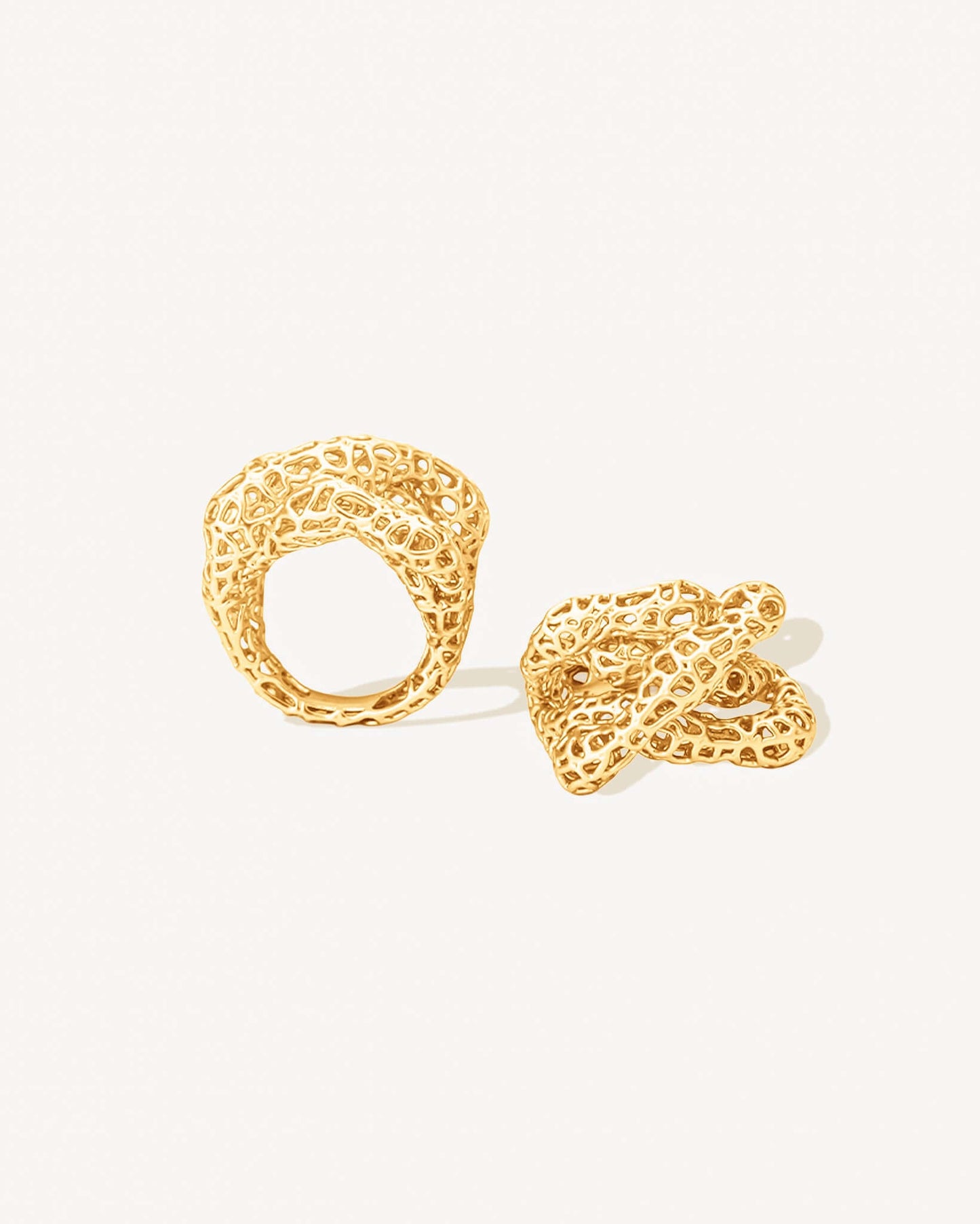 Gold open-work knot ring with a sculptural, intertwined design and wide textured band. This chunky statement ring features organic cutout details that create a bold yet airy look. Crafted in polished gold-tone metal, it blends modern artistry with everyday wearability — ideal as a solo statement piece or stacked with minimalist bands.