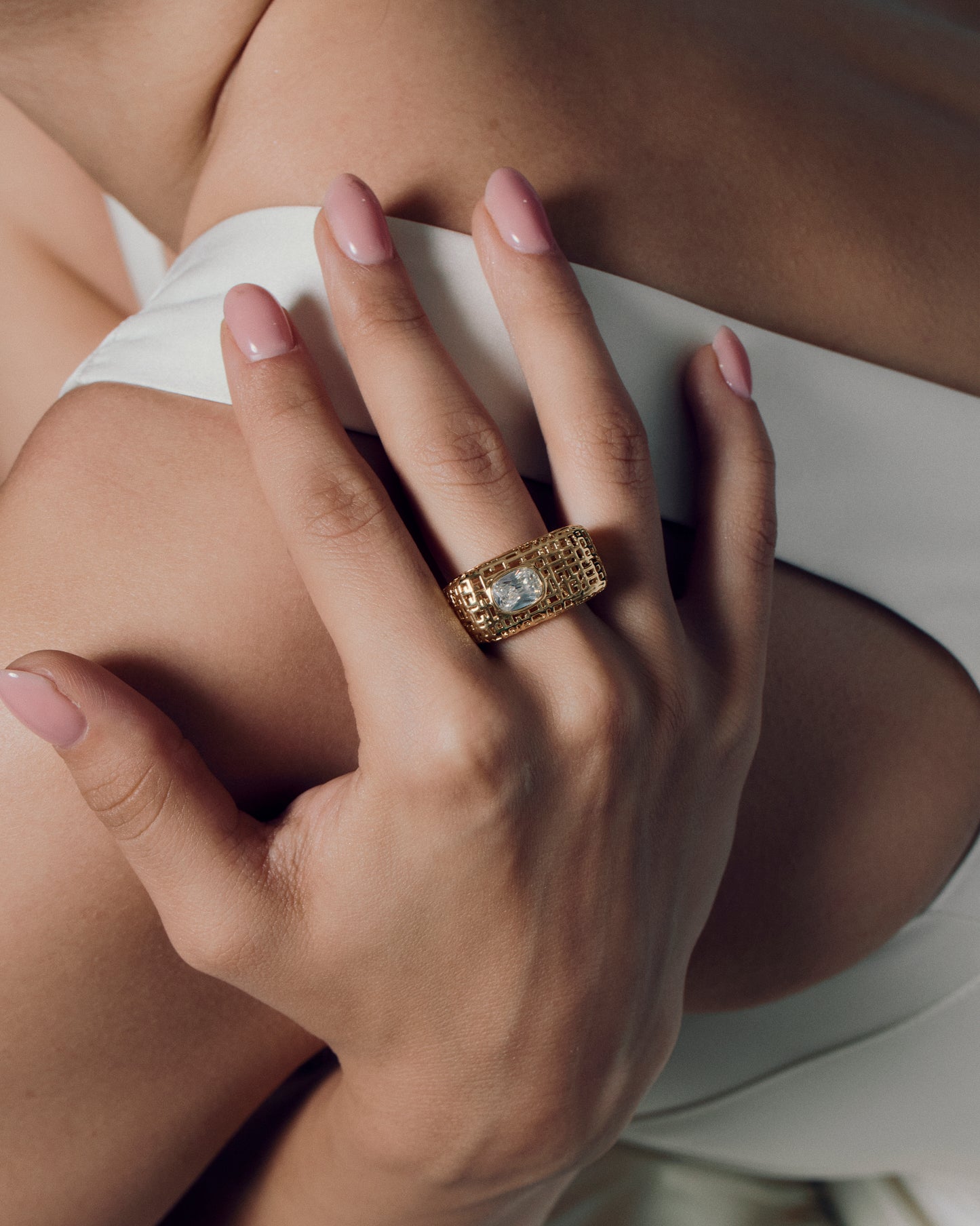 Model wearing open work square gold ring with clear stone, showing the chunky sculptural texture and modern grid-pattern design. A bold gold statement ring that elevates everyday style or evening wear, highlighting its geometric shape and luxurious finish for a refined yet artistic look.