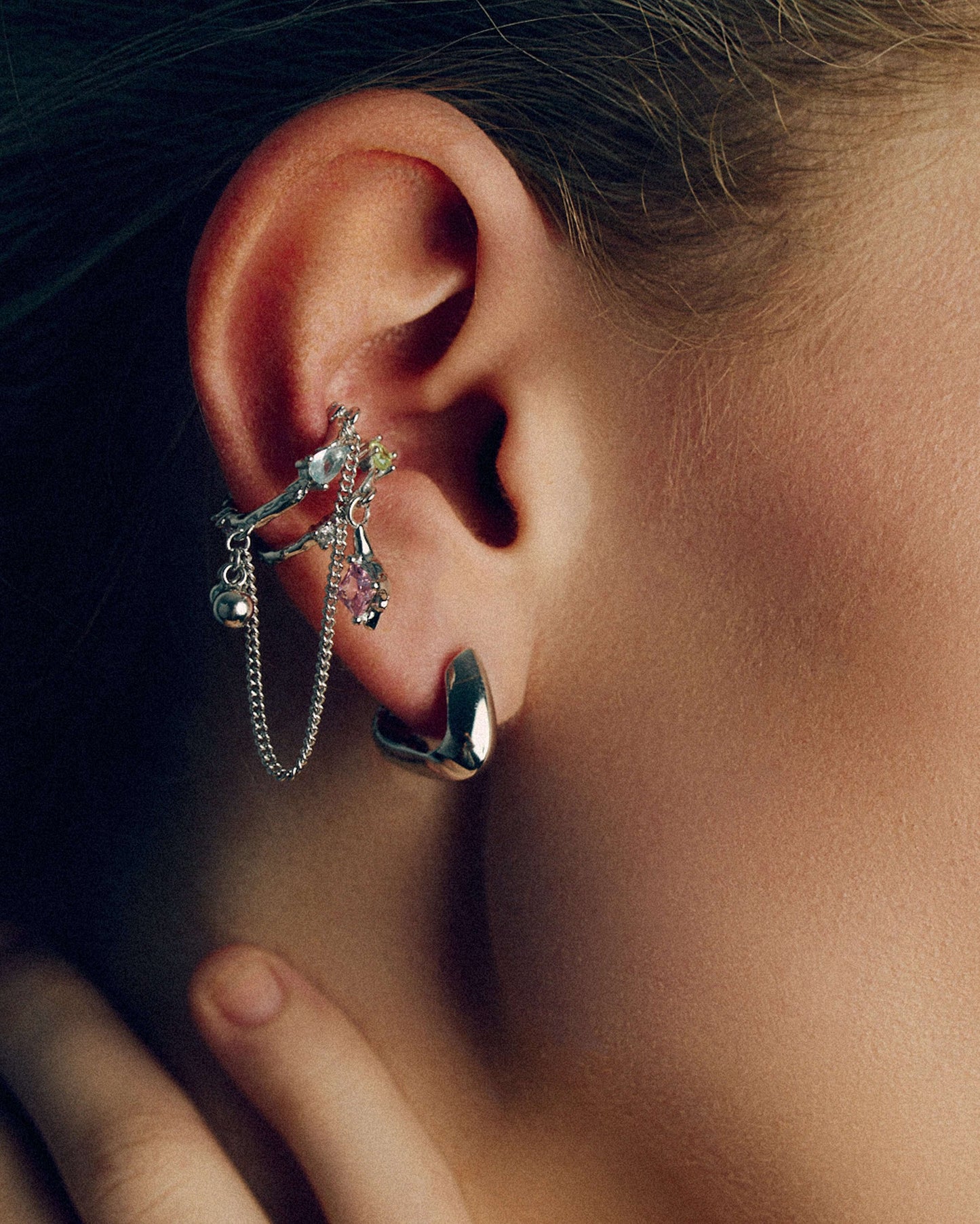 Gold and silver ear cuffs with dangling chains, charms, and colorful cubic zirconia stones. Non-pierced adjustable cartilage cuffs featuring teardrop and square-cut gems for a bold, playful, and trendy statement look.