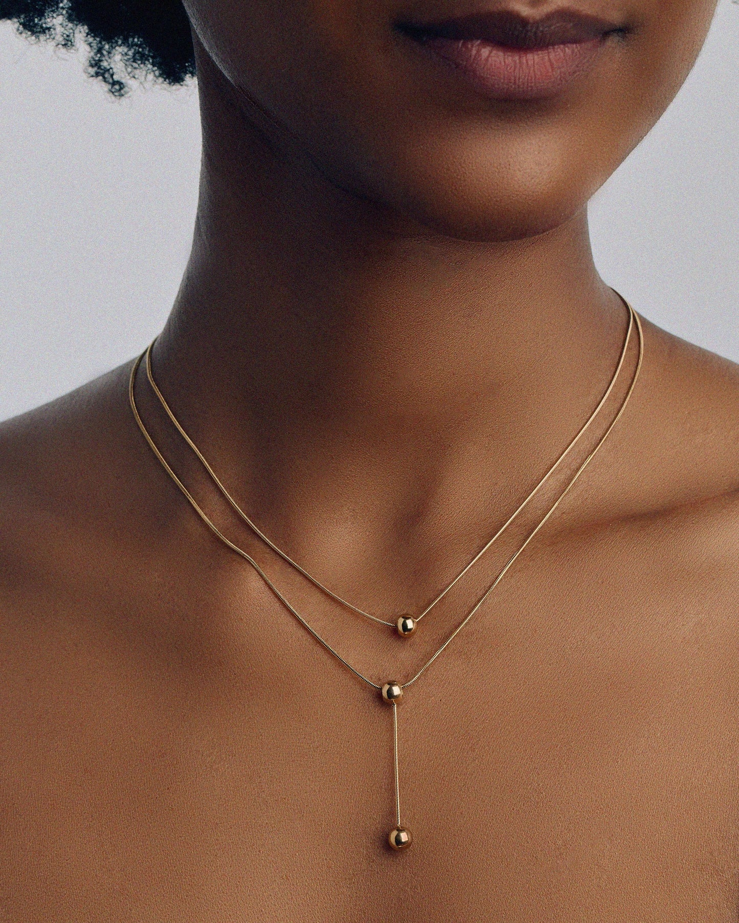 Double-strand 18K gold plated necklace with layered chains and polished ball pendants, delicate and modern for everyday or statement wear.
