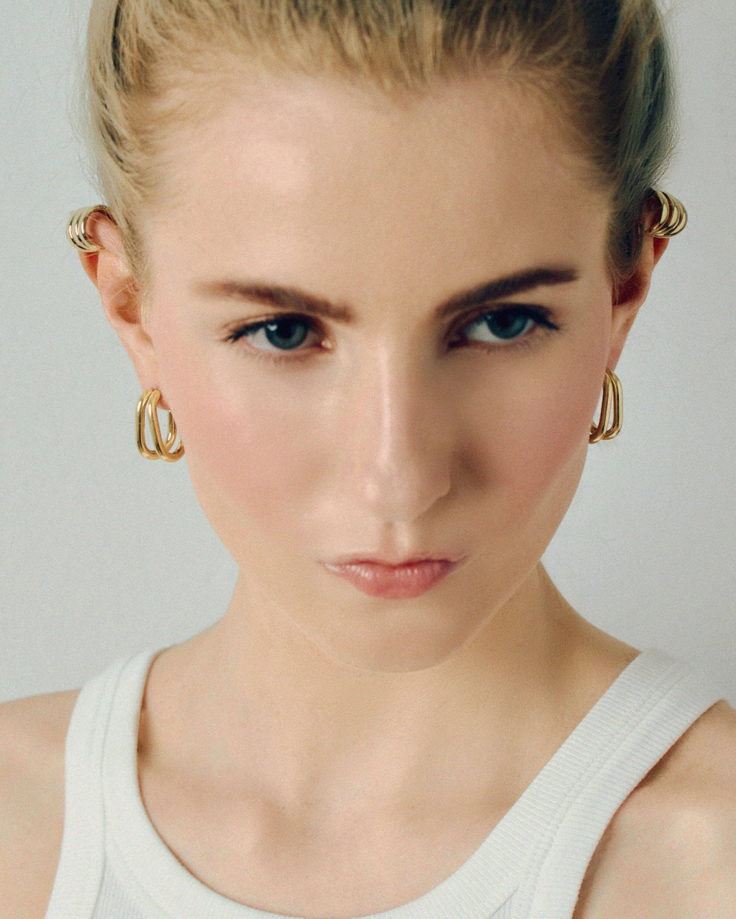 Gold double hoop earrings featuring two thick, sculptural curved bands with a polished high-shine finish. Modern layered design with secure post backs, creating a bold yet minimalist statement. Perfect for everyday wear or adding a stylish, contemporary touch to any outfit.
