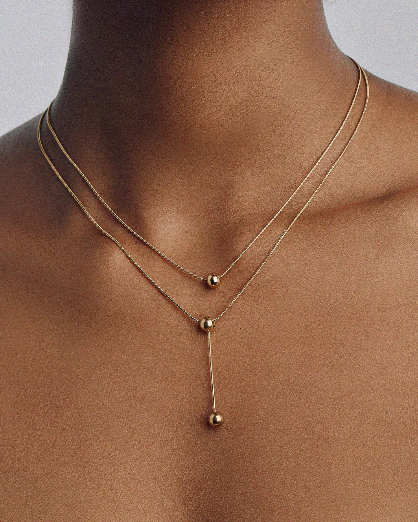 Double-strand 18K gold plated necklace with layered chains and polished ball pendants, delicate and modern for everyday or statement wear.
