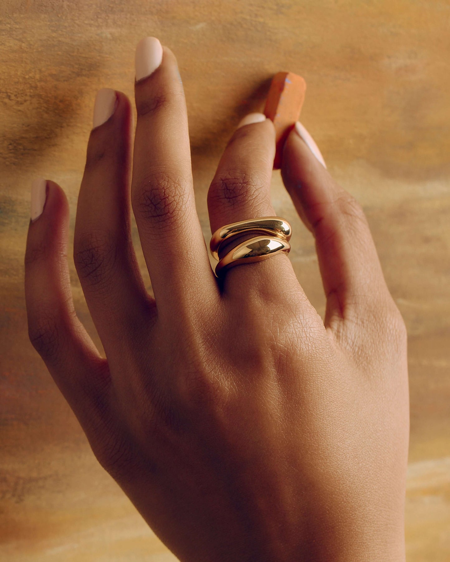 Gold layered sculptural ring with smooth stacked design, minimal statement band worn on hand
