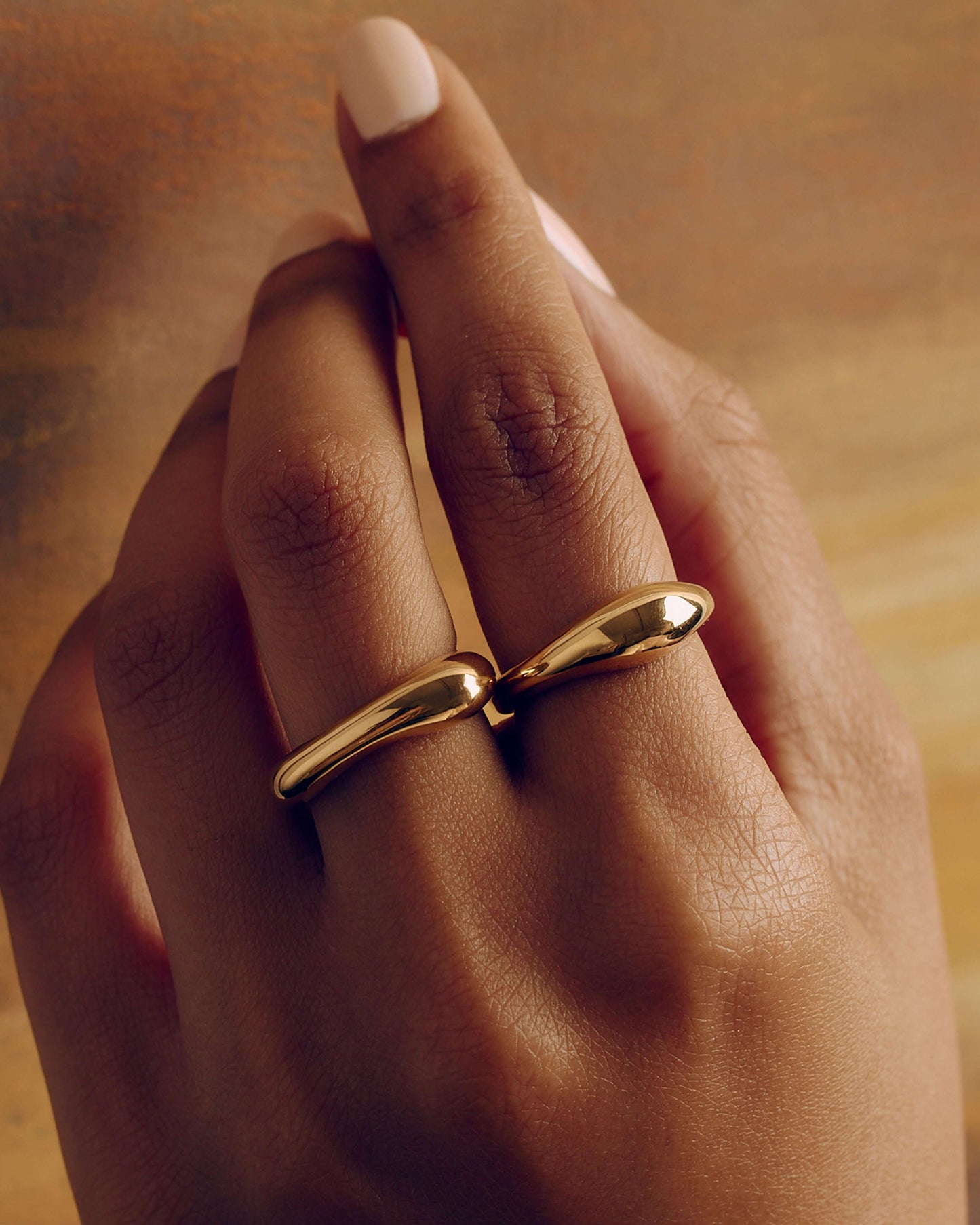 Gold layered sculptural ring with smooth stacked design, minimal statement band worn on hand
