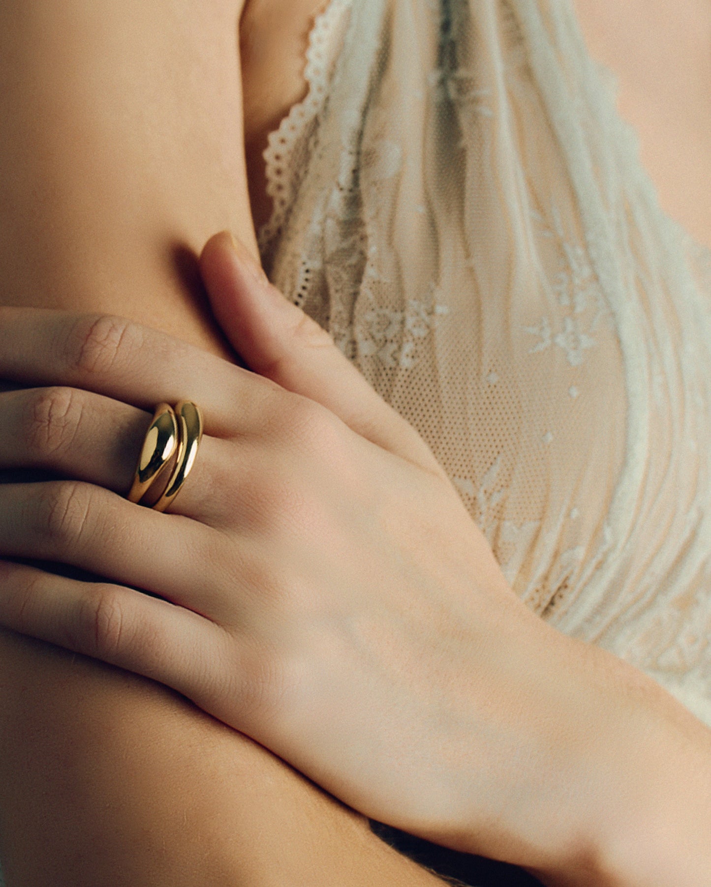 Gold layered sculptural ring with smooth stacked design, minimal statement band worn on hand