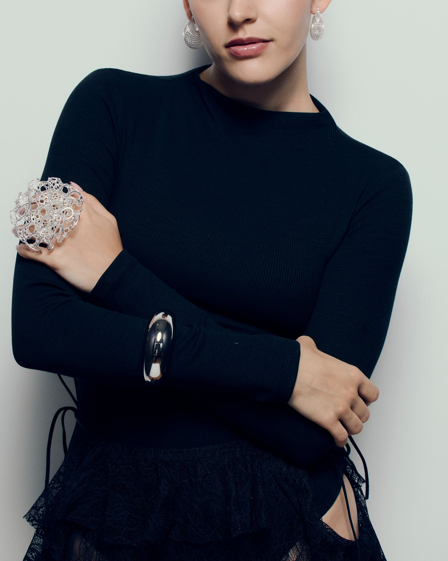 Close-up of a sculptural open-work statement ring featuring organic, lattice-like curves that flow across the fingers. The bold, artistic design catches light and shadow, creating a striking balance of size and airiness. Perfect for modern, contemporary, and architectural jewelry lovers who appreciate wearable art.