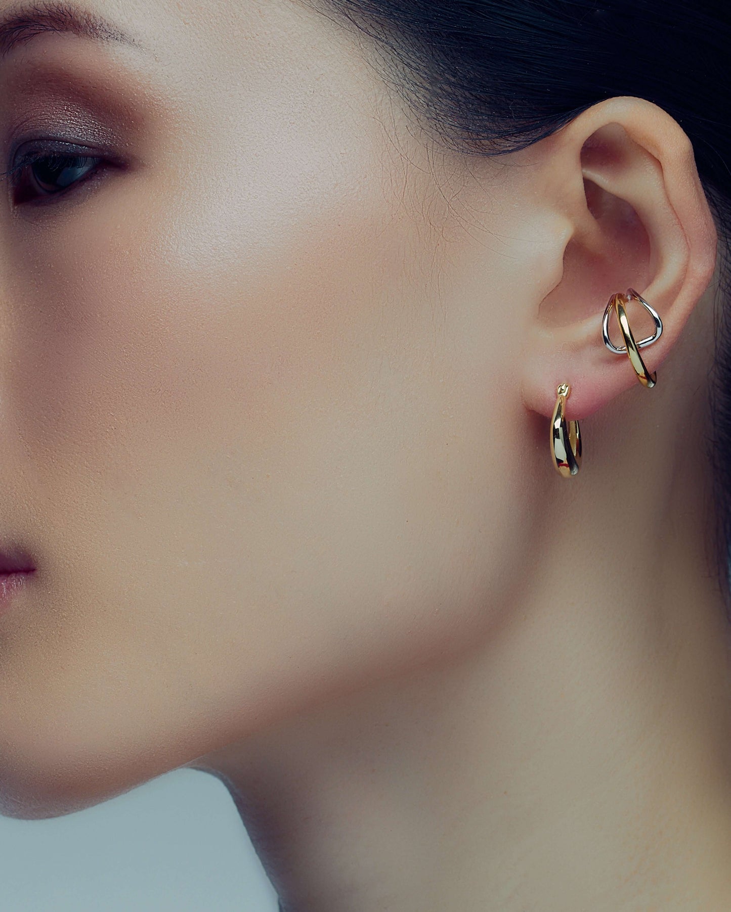 Two-tone ear cuff featuring a sleek wrap-around design in gold and silver, offering a modern, non-pierced accessory for versatile styling.
