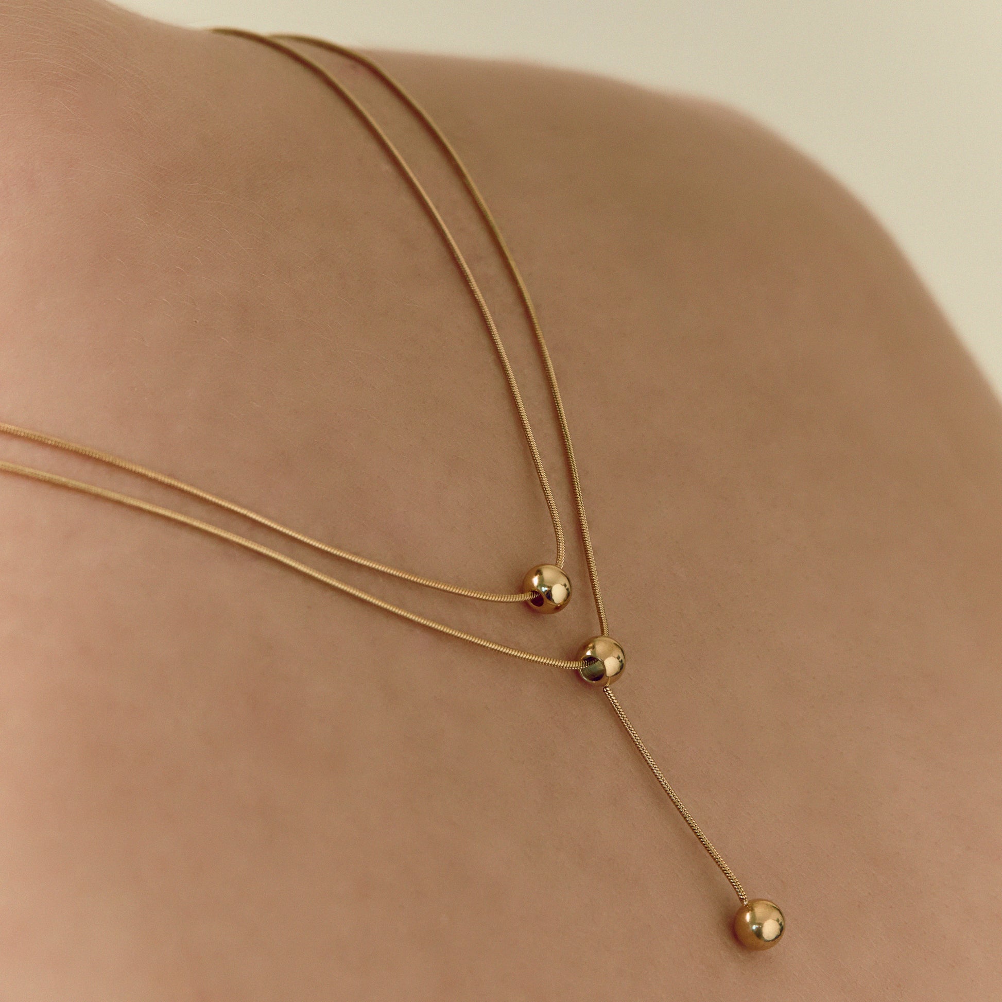 Double-strand 18K gold plated necklace with layered chains and polished ball pendants, delicate and modern for everyday or statement wear.