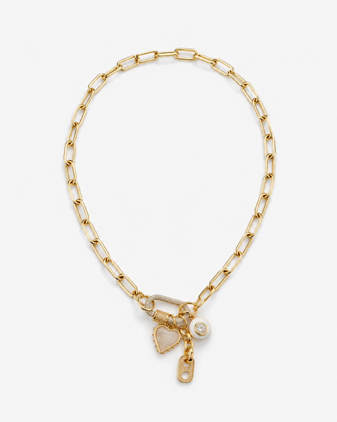 A gold paperclip chain bracelet with a lobster clasp, featuring a dangling heart-shaped charm, a small round charm, and a tiny tag charm, all on a clean white background.