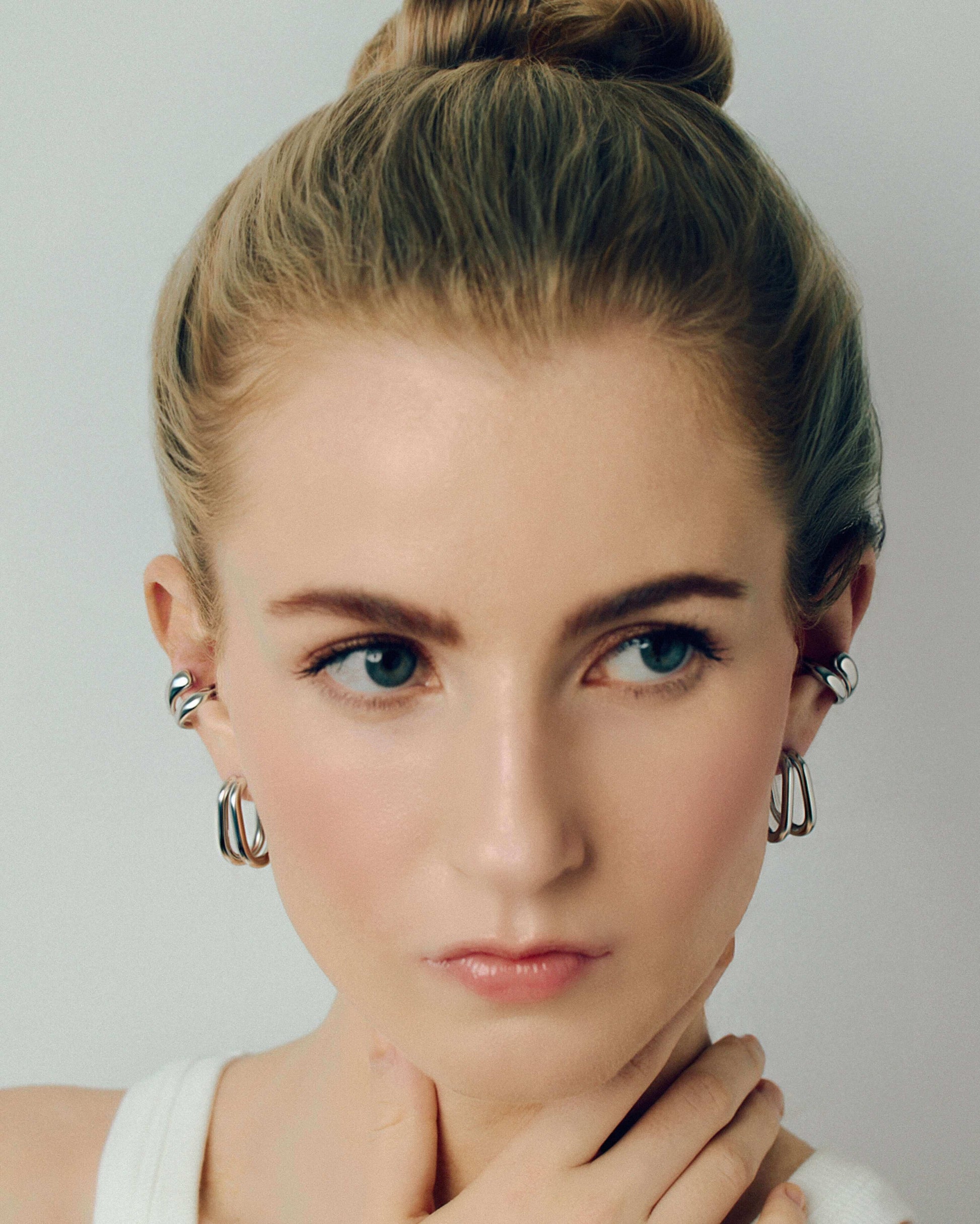 Gold double hoop earrings featuring two thick, sculptural curved bands with a polished high-shine finish. Modern layered design with secure post backs, creating a bold yet minimalist statement. Perfect for everyday wear or adding a stylish, contemporary touch to any outfit.