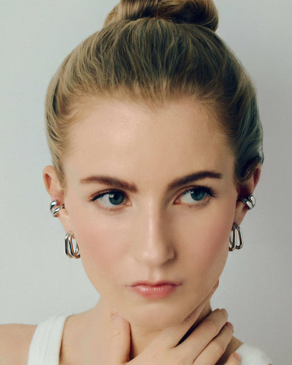 Gold double hoop earrings featuring two thick, sculptural curved bands with a polished high-shine finish. Modern layered design with secure post backs, creating a bold yet minimalist statement. Perfect for everyday wear or adding a stylish, contemporary touch to any outfit.