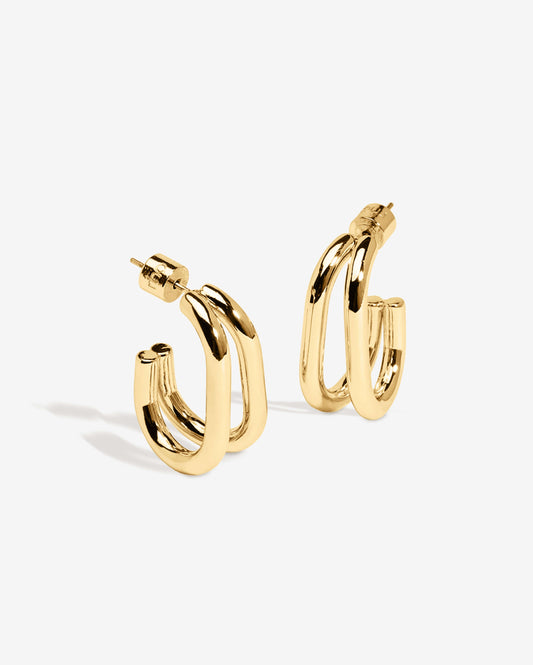 Gold double hoop earrings featuring two thick, sculptural curved bands with a polished high-shine finish. Modern layered design with secure post backs, creating a bold yet minimalist statement. Perfect for everyday wear or adding a stylish, contemporary touch to any outfit.