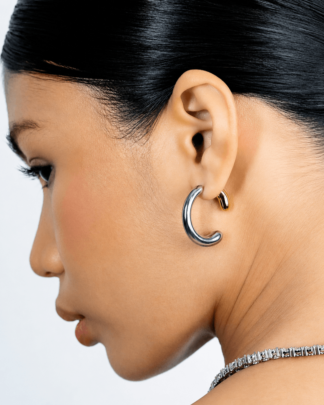 Two tone gold and silver 360 front back hoop earrings displayed on a soft neutral background. Modern sculptural shape hoop earrings with chunky curved silhouette, minimalist statement jewelry designed for contemporary everyday wear.