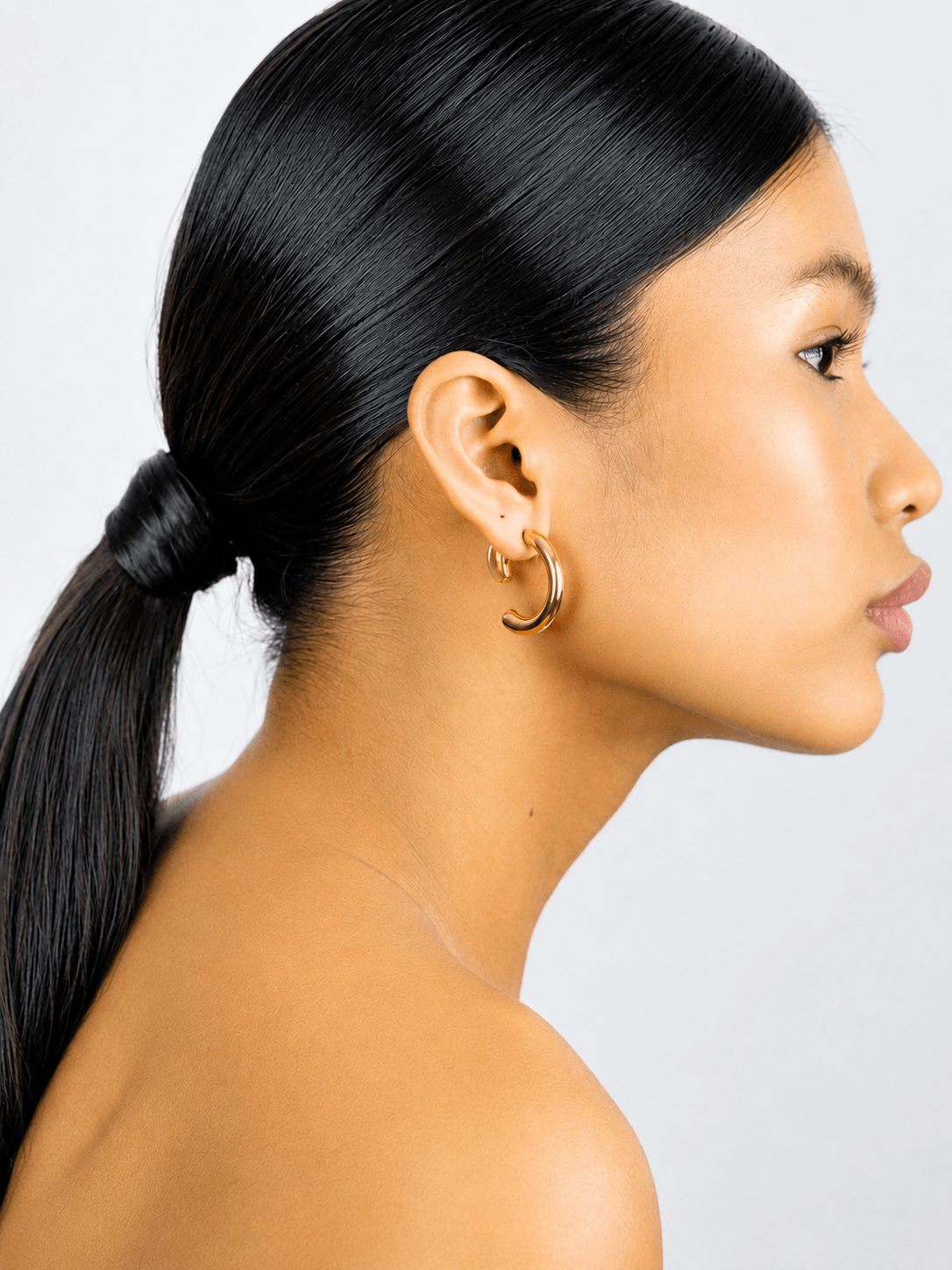 Two tone gold and silver 360 front back hoop earrings displayed on a soft neutral background. Modern sculptural shape hoop earrings with chunky curved silhouette, minimalist statement jewelry designed for contemporary everyday wear.