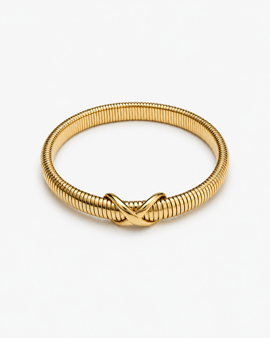 Knot bangle bracelet in gold and silver with flexible ribbed coil design and sculptural knot detail