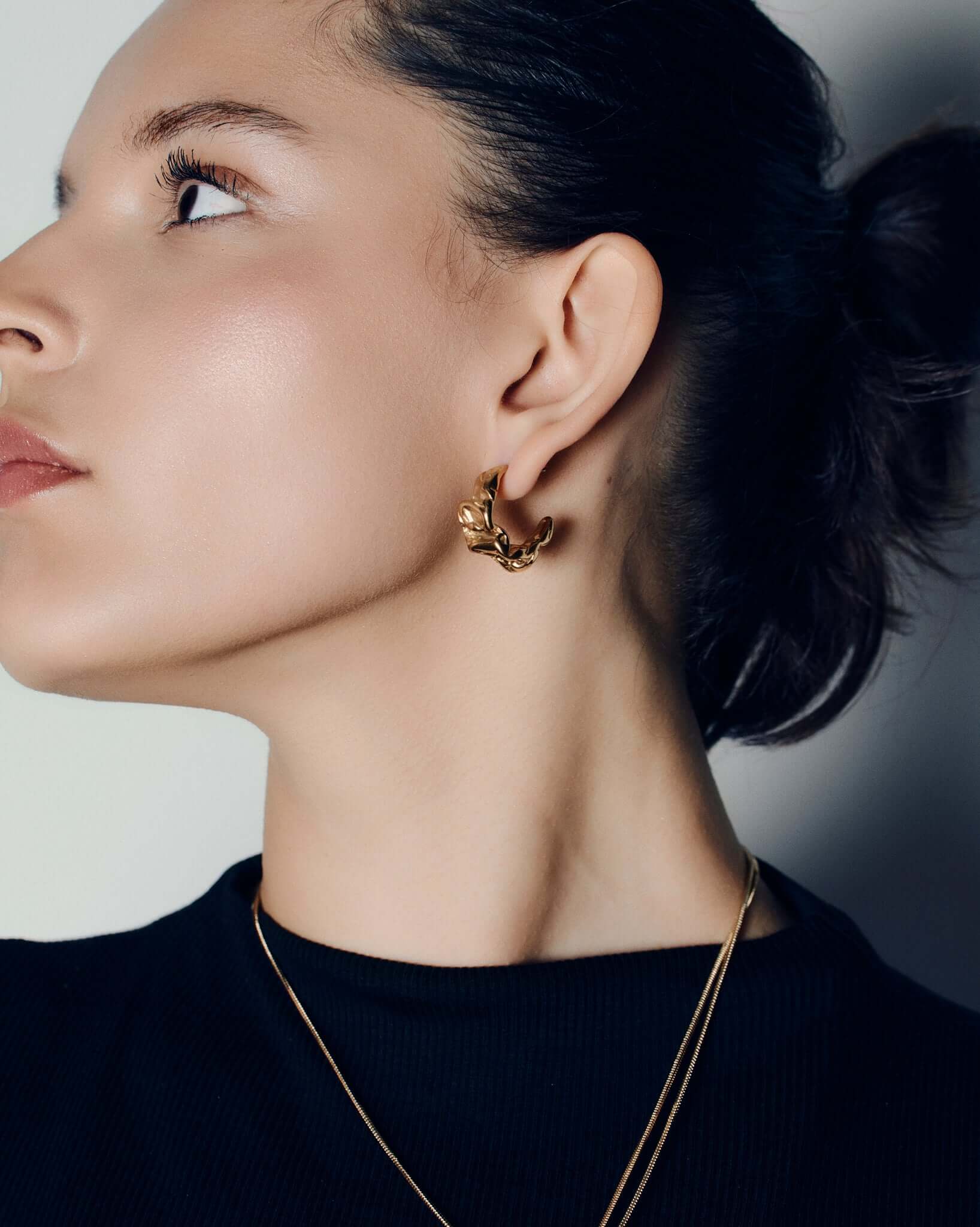 Molten design gold hoop earrings featuring a sculptural, fluid silhouette with polished curves and a high-shine finish. These statement hoops capture the organic flow of molten metal, blending bold form with refined minimalism. Perfect for everyday wear or evening looks, they add effortless sophistication and modern edge to any outfit.