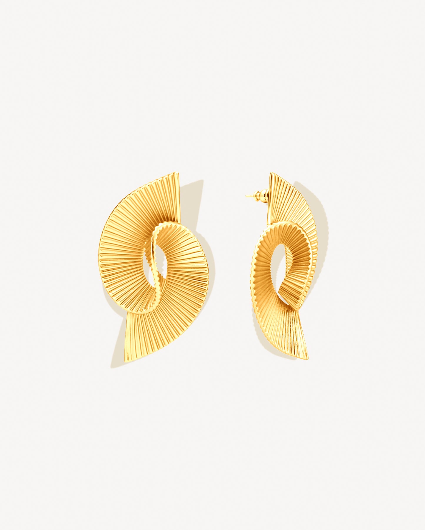 Pleated sculptural gold earrings featuring a twisted, folded design with fine ridged texture. These bold statement earrings have an open curved form that adds dimension and movement. Crafted in polished gold-tone metal, they bring a modern, architectural edge to any outfit — lightweight yet striking for everyday or occasion wear.
