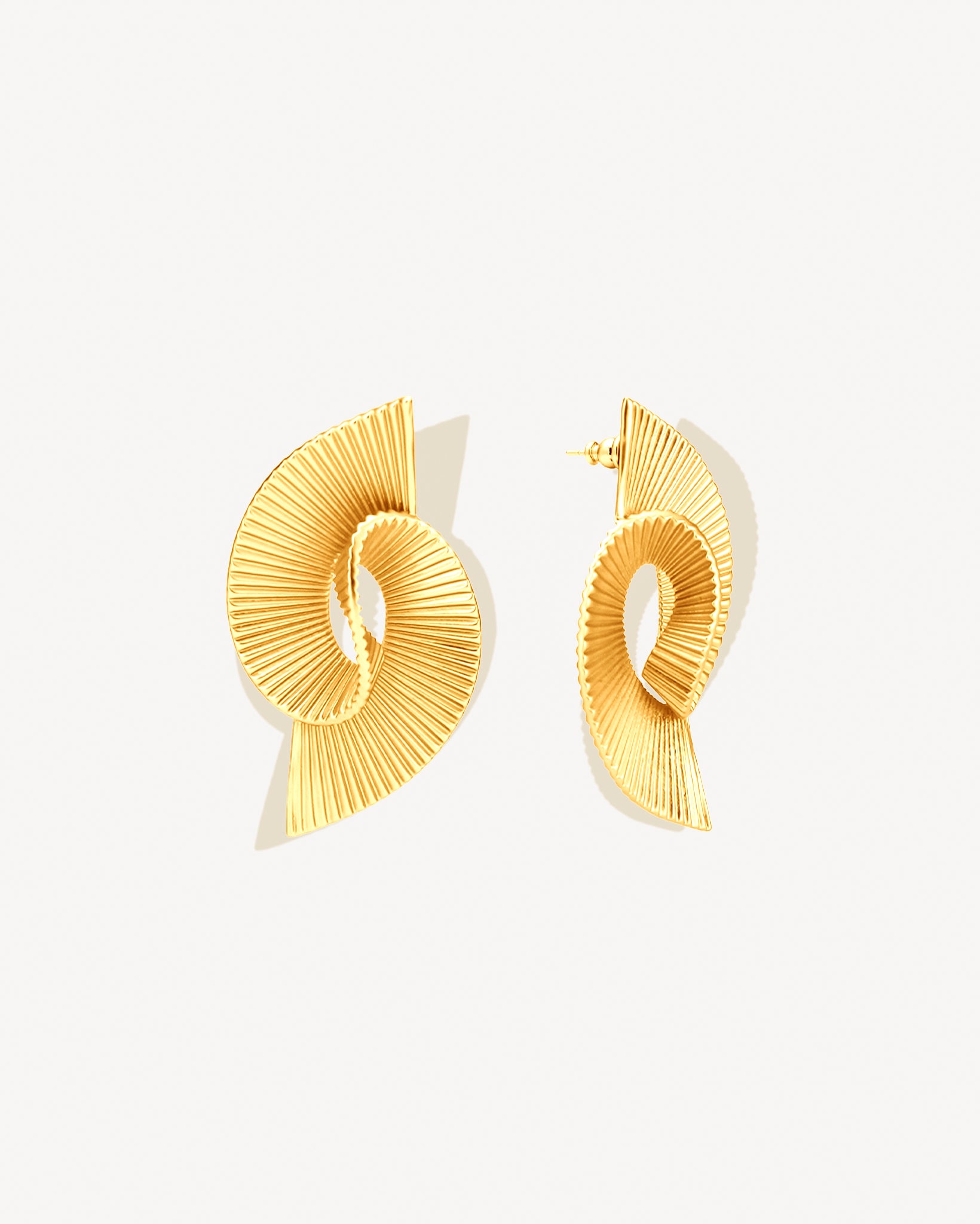 Pleated sculptural gold earrings featuring a twisted, folded design with fine ridged texture. These bold statement earrings have an open curved form that adds dimension and movement. Crafted in polished gold-tone metal, they bring a modern, architectural edge to any outfit — lightweight yet striking for everyday or occasion wear.