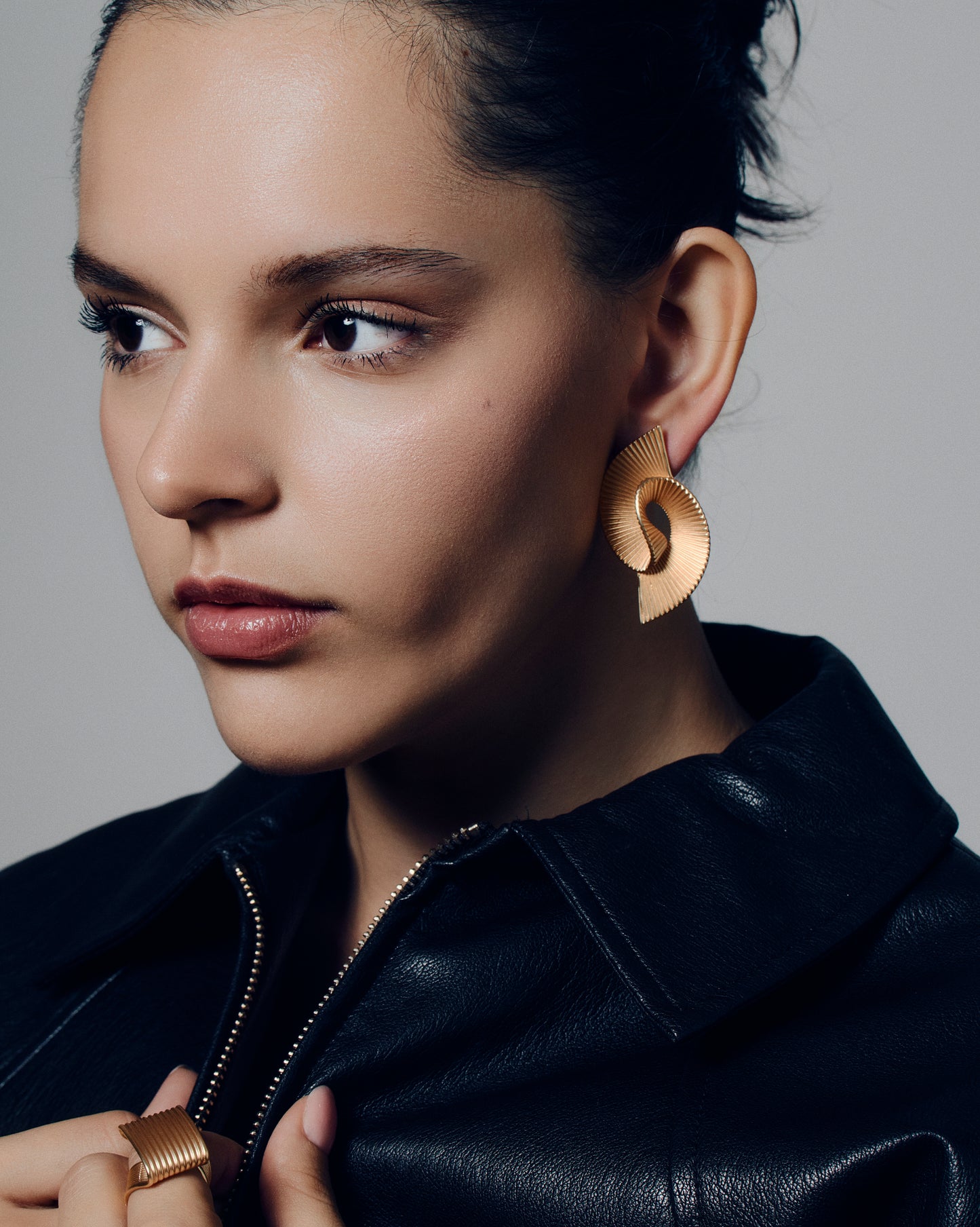 Pleated sculptural gold earrings featuring a twisted, folded design with fine ridged texture. These bold statement earrings have an open curved form that adds dimension and movement. Crafted in polished gold-tone metal, they bring a modern, architectural edge to any outfit — lightweight yet striking for everyday or occasion wear.