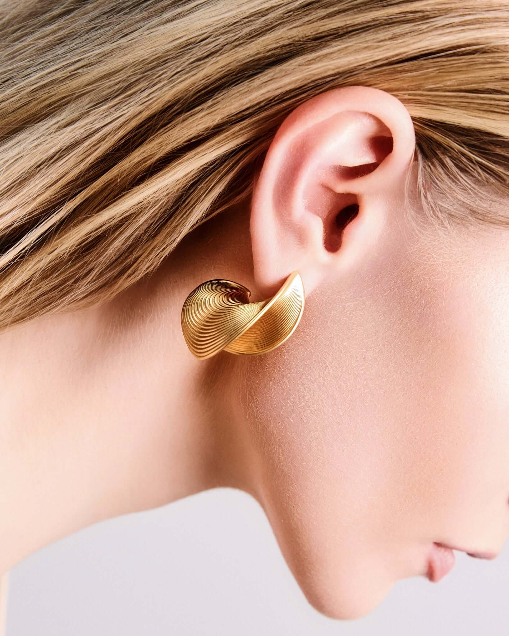 Sculptural ribbed hoop earrings in gold finish, bold textured statement hoops for women, modern curved hoop earrings, contemporary minimalist jewelry, chunky ribbed gold earrings for everyday wear or elevated evening styling