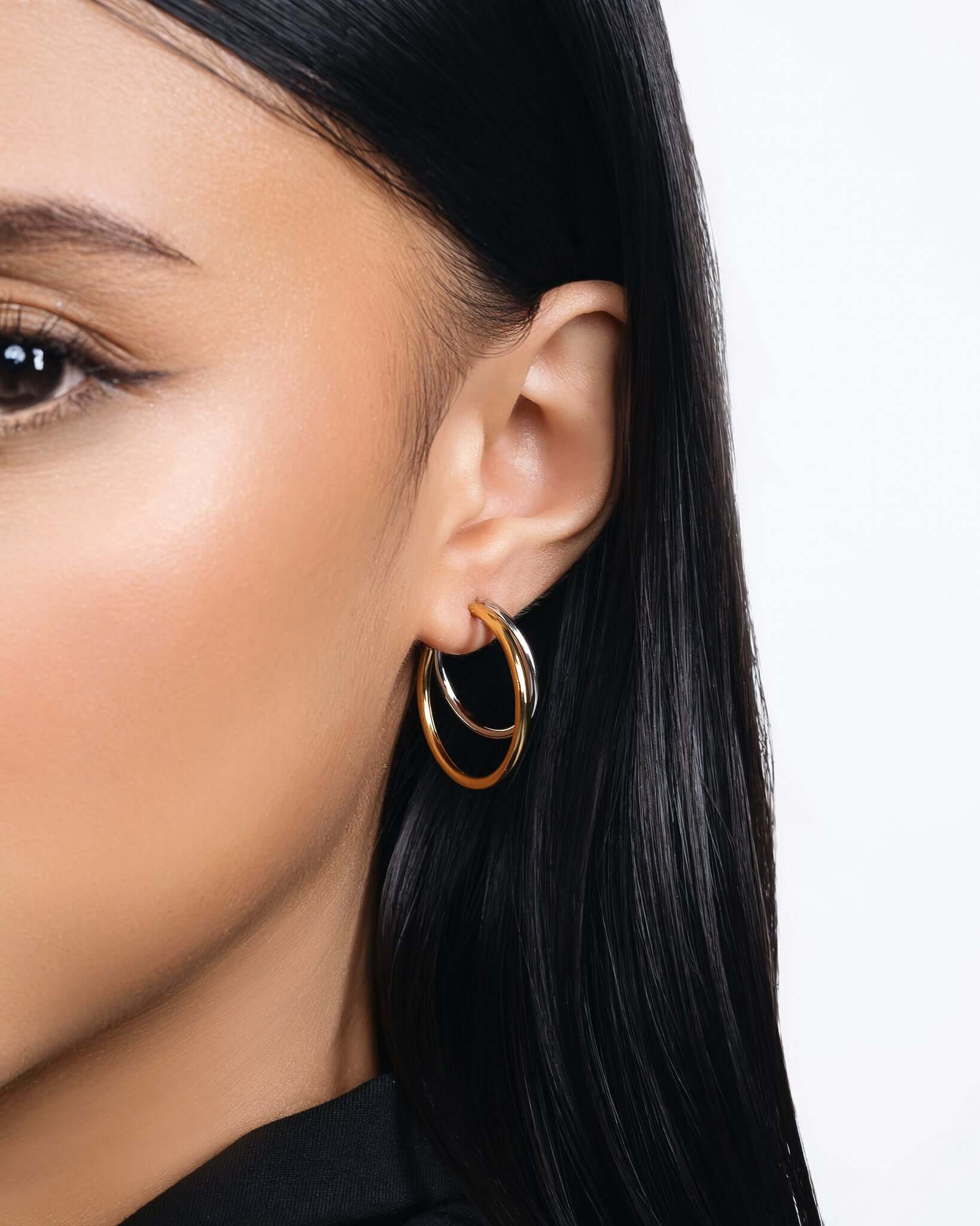 Modern two tone double hoop earrings featuring a polished gold outer hoop and silver inner hoop with secure tube lock closure, minimalist mixed metal statement earrings for everyday wear and modern jewelry styling.