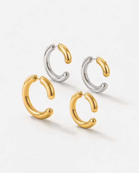 Two tone gold and silver 360 front back hoop earrings displayed on a soft neutral background. Modern sculptural shape hoop earrings with chunky curved silhouette, minimalist statement jewelry designed for contemporary everyday wear.