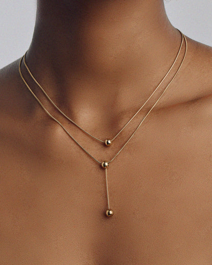 Double-strand 18K gold plated necklace with layered chains and polished ball pendants, delicate and modern for everyday or statement wear.