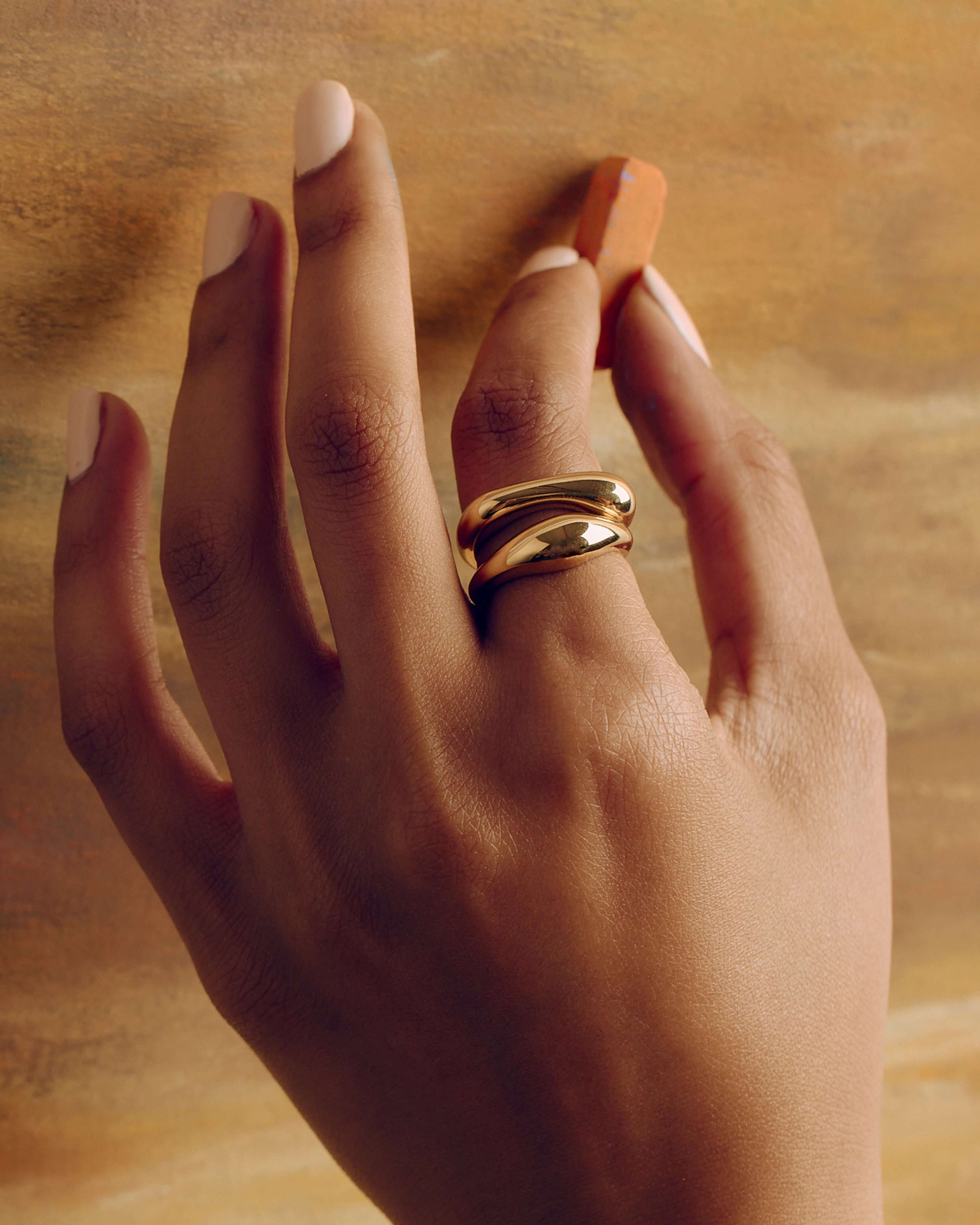 Gold layered sculptural ring with smooth stacked design, minimal statement band worn on hand