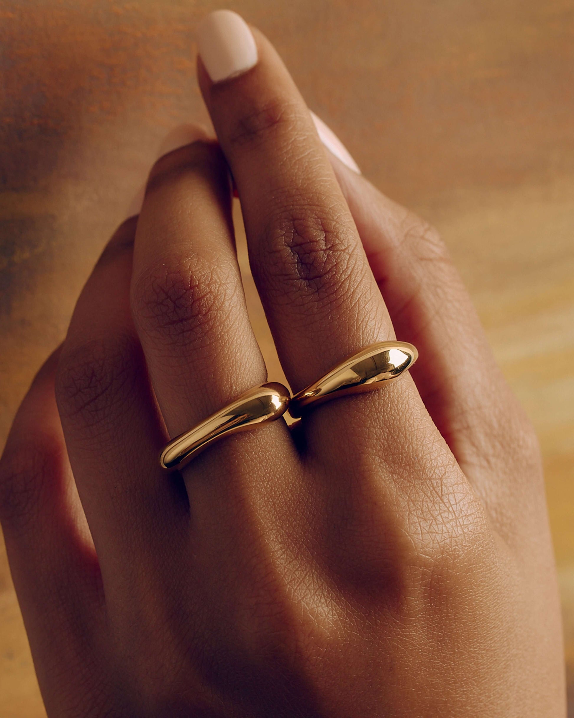 Gold layered sculptural ring with smooth stacked design, minimal statement band worn on hand