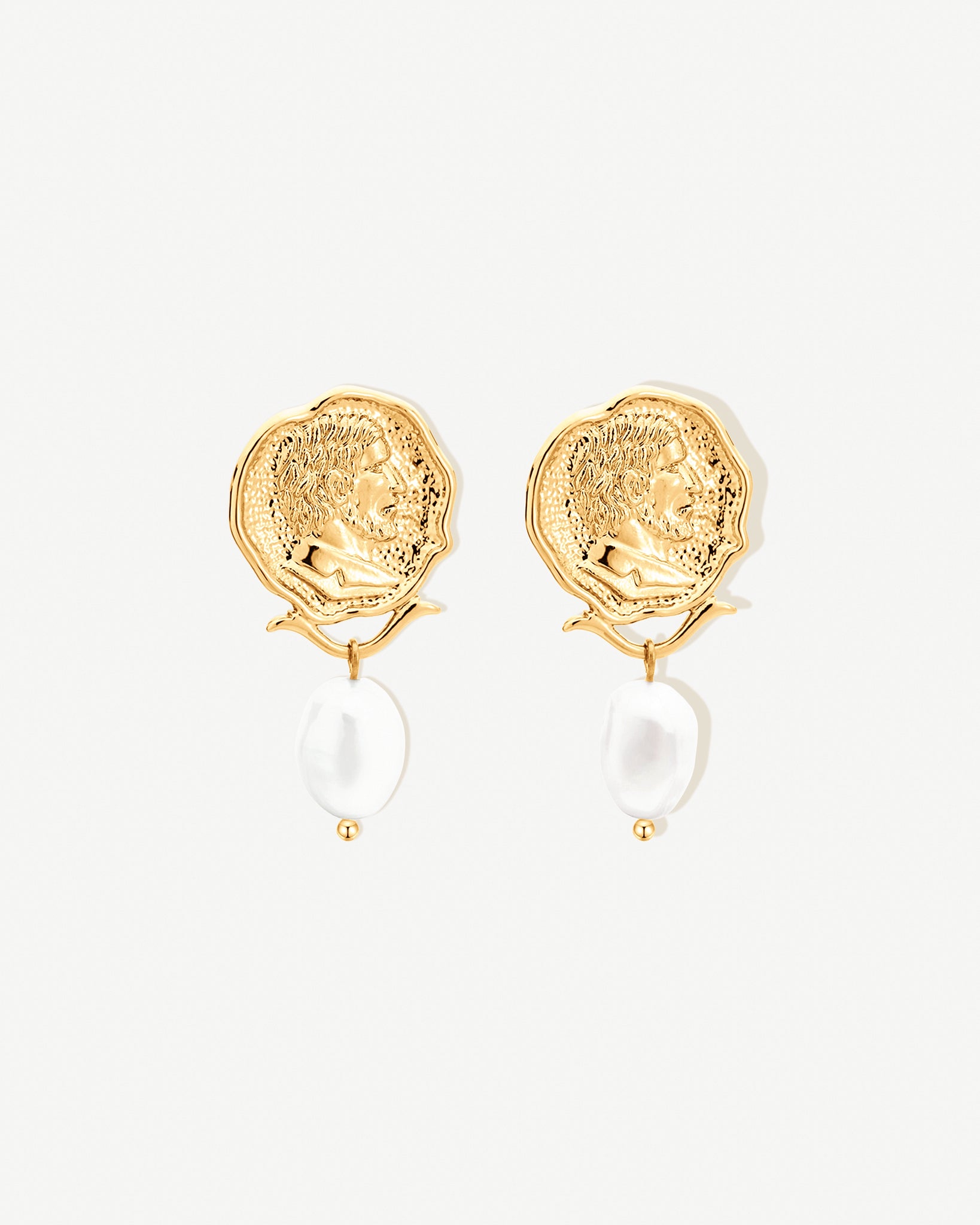 Gold earrings with medallion engraving and pearl drop on a white background