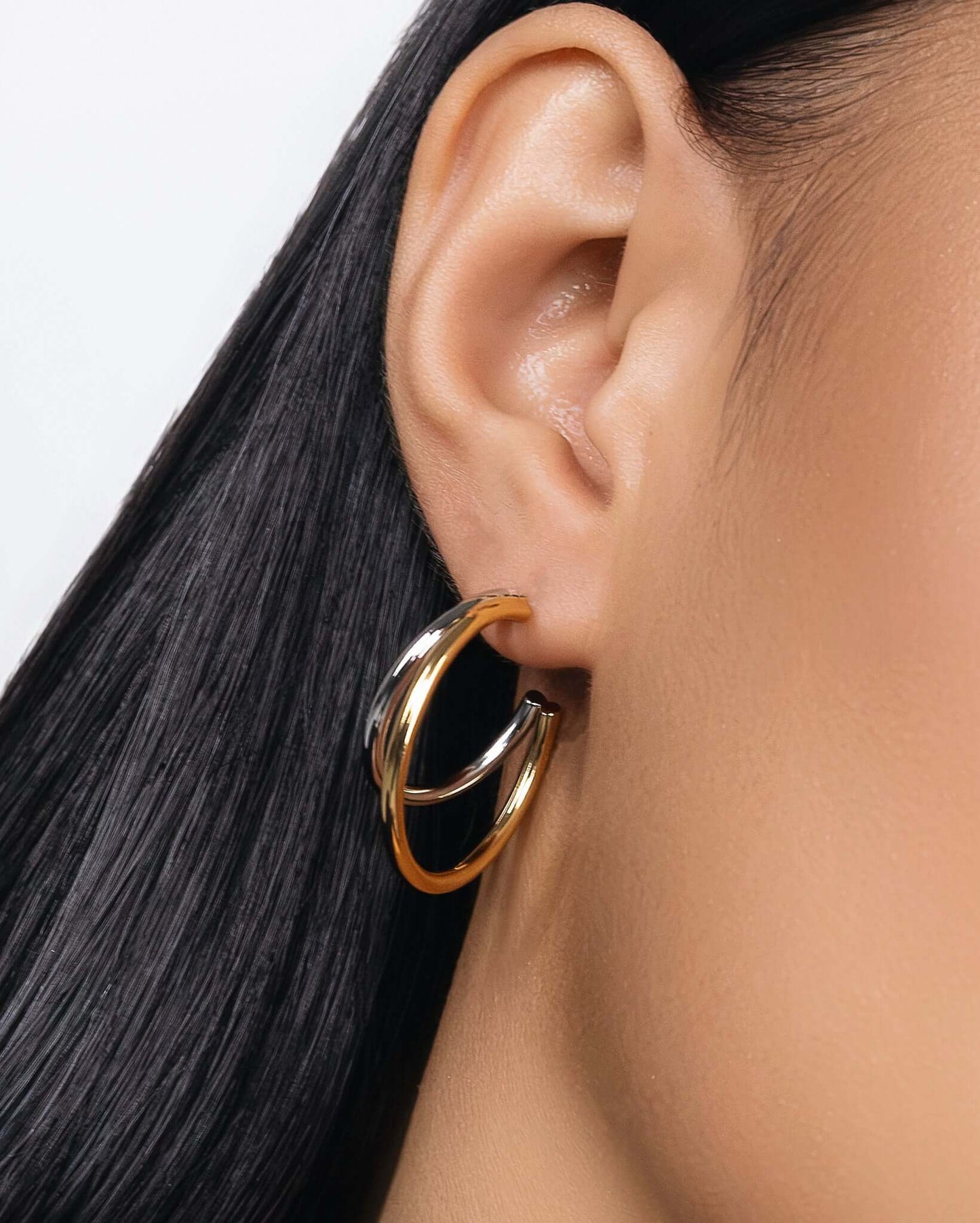 Modern two tone double hoop earrings featuring a polished gold outer hoop and silver inner hoop with secure tube lock closure, minimalist mixed metal statement earrings for everyday wear and modern jewelry styling.