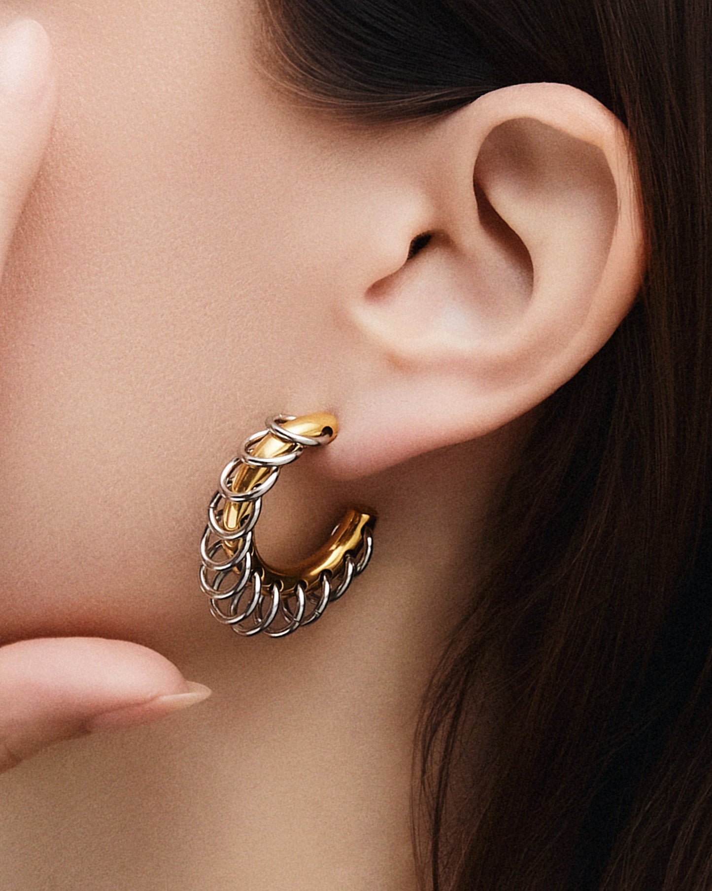 Two-tone chunky hoop earrings featuring interlocking gold and silver loops in a sculptural, modern design. The mixed-metal finish creates a bold yet refined statement look, perfect for everyday wear or special occasions. These contemporary hoops add dimension and shine, effortlessly complementing minimalist or statement jewelry styles. Ideal for those who love elevated, modern accessories.