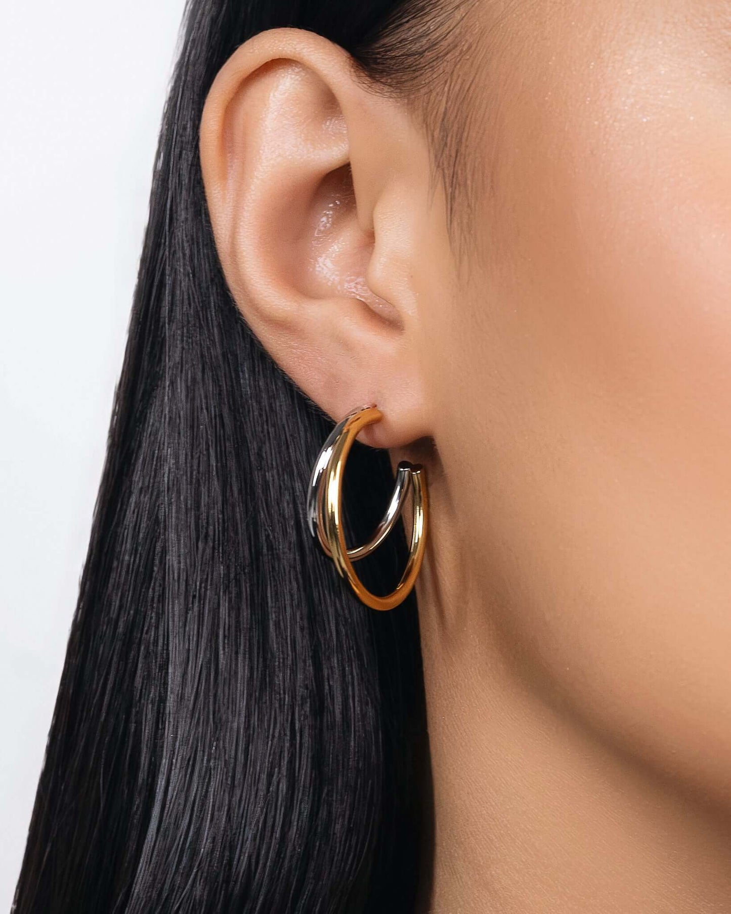 Modern two tone double hoop earrings featuring a polished gold outer hoop and silver inner hoop with secure tube lock closure, minimalist mixed metal statement earrings for everyday wear and modern jewelry styling.