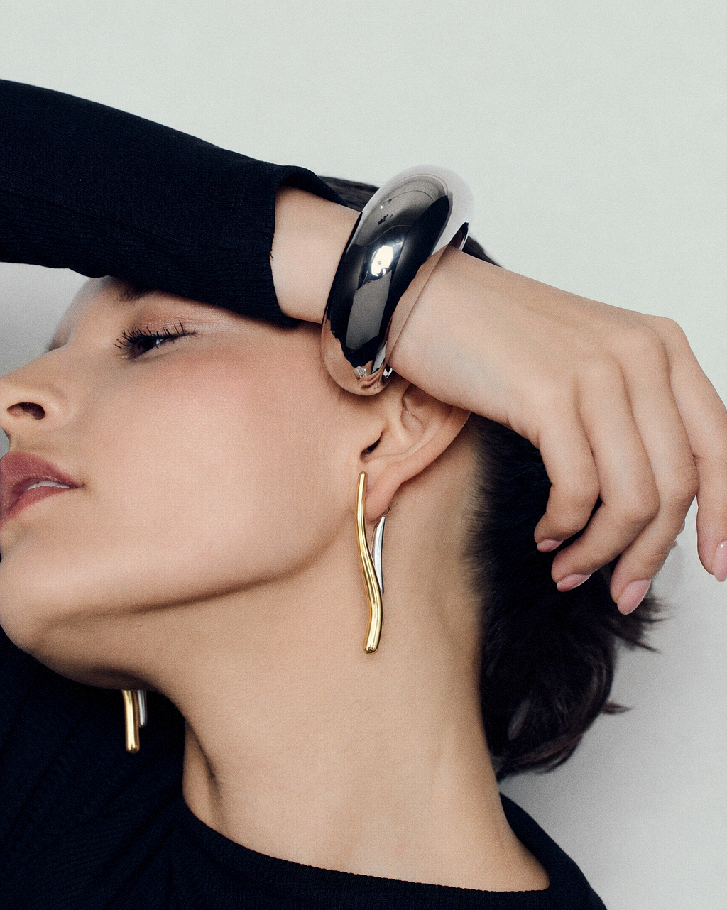 Two tone ear jacket earrings in polished gold and silver with sculptural curved bars, teardrop drop details and a modern mixed metal statement design by RRule