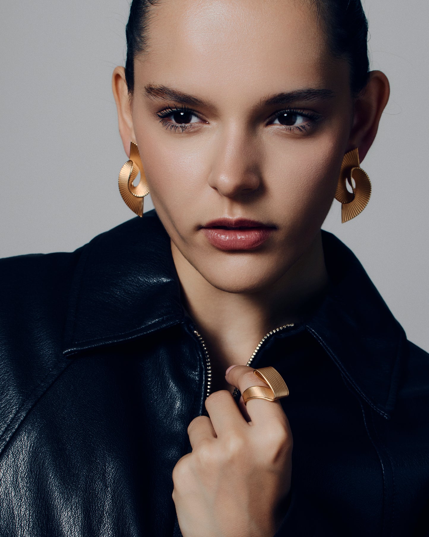 Pleated sculptural gold earrings featuring a twisted, folded design with fine ridged texture. These bold statement earrings have an open curved form that adds dimension and movement. Crafted in polished gold-tone metal, they bring a modern, architectural edge to any outfit — lightweight yet striking for everyday or occasion wear.