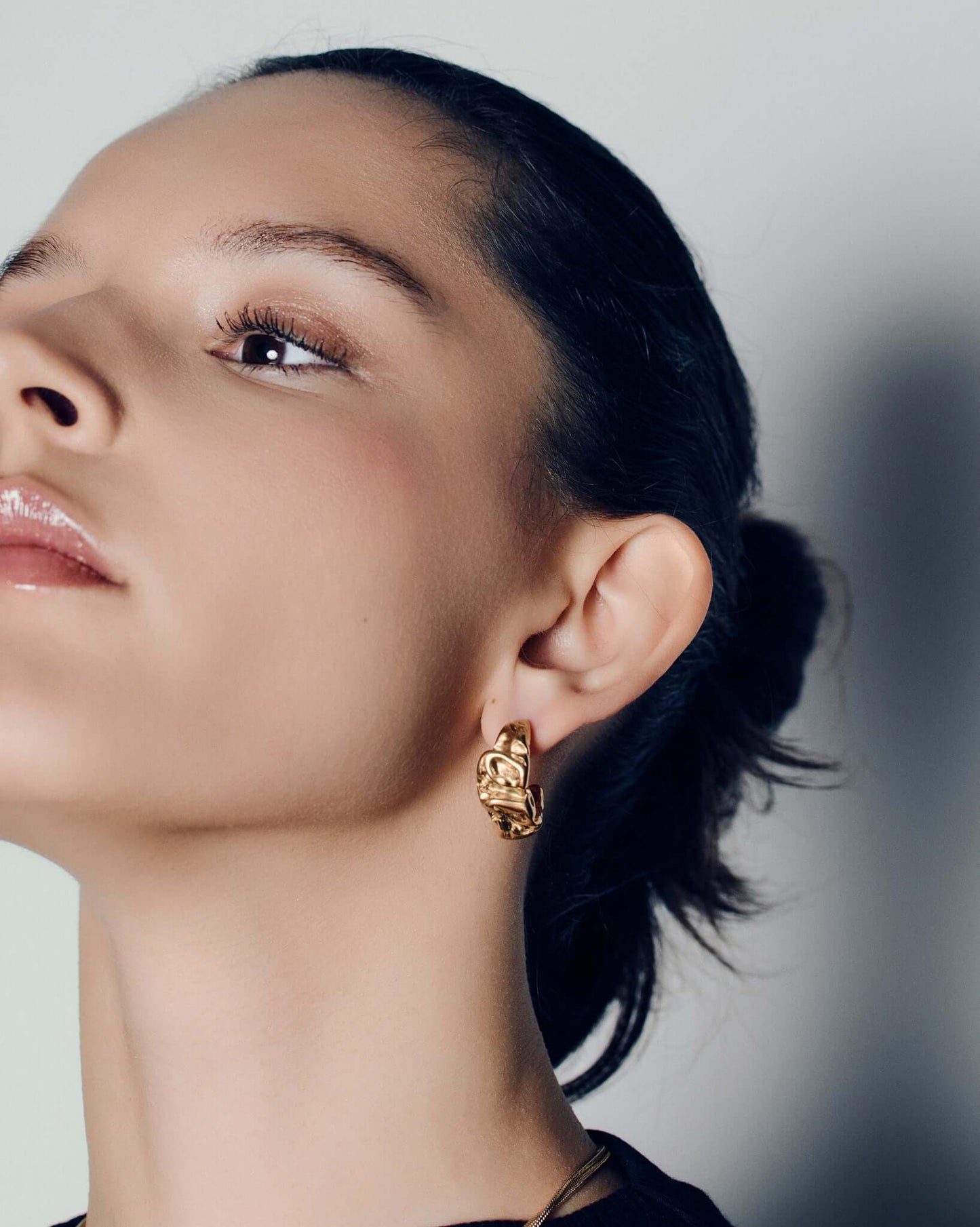 Molten design gold hoop earrings featuring a sculptural, fluid silhouette with polished curves and a high-shine finish. These statement hoops capture the organic flow of molten metal, blending bold form with refined minimalism. Perfect for everyday wear or evening looks, they add effortless sophistication and modern edge to any outfit.