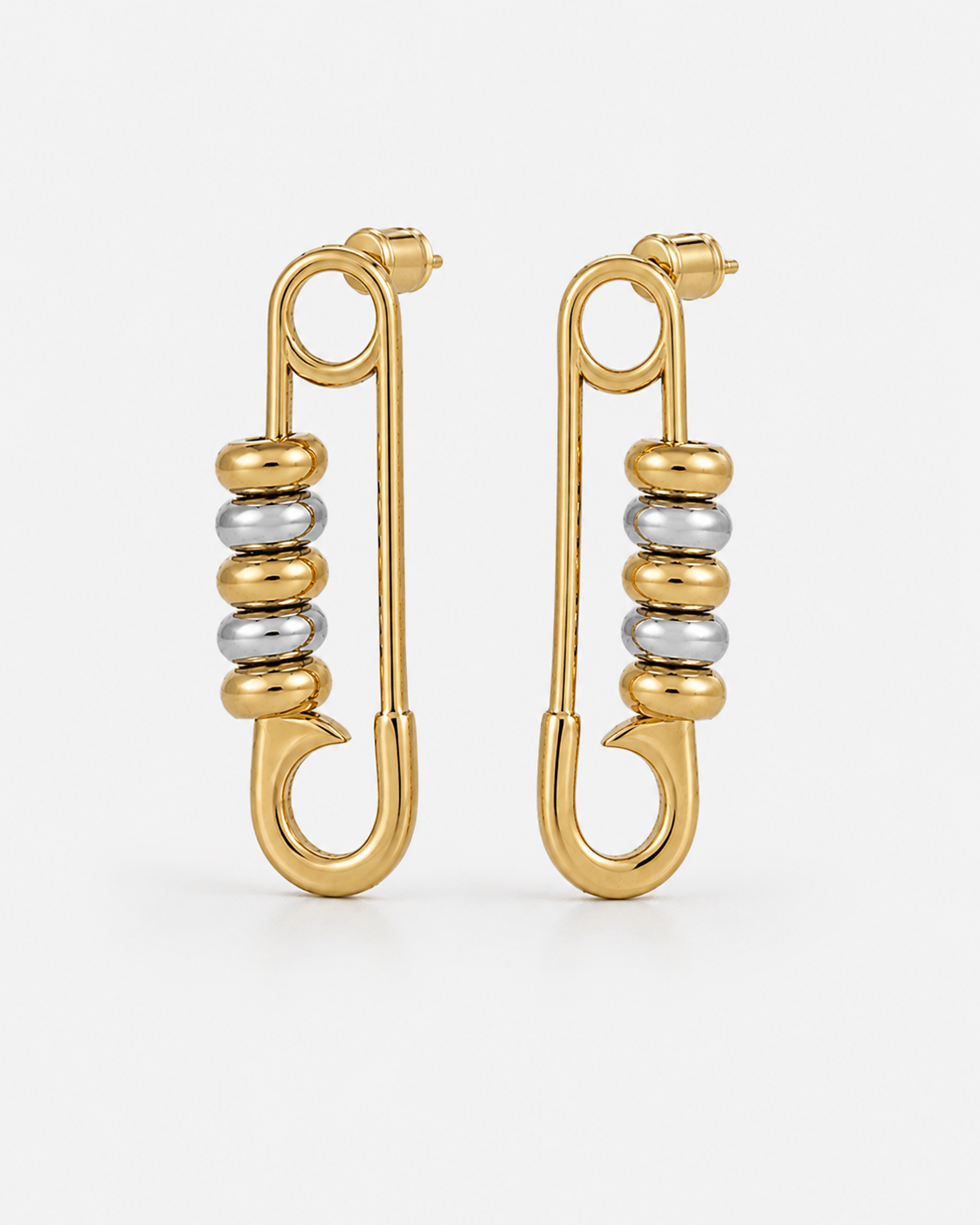 Gold safety pin earrings with silver bead details worn on ear, chunky statement earrings for women, modern two tone jewelry, edgy minimalist gold hoop earrings, trendy everyday fashion accessory, unique punk inspired earrings, stainless steel safety pin d