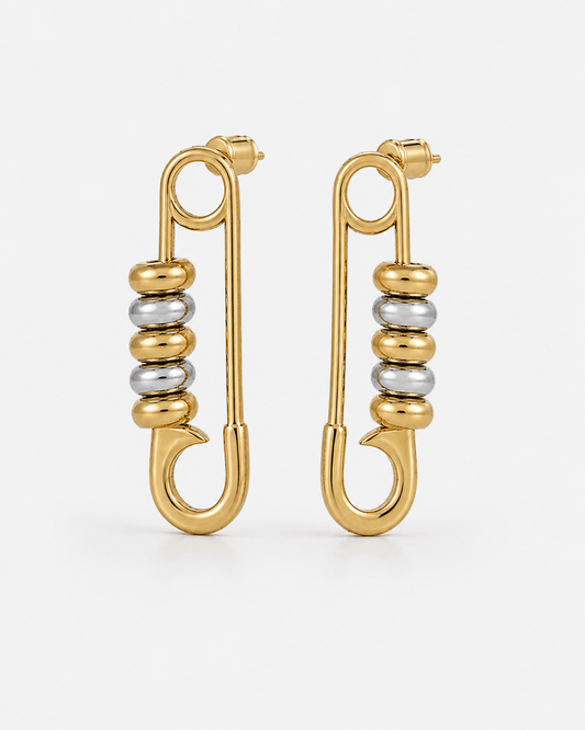 Gold safety pin earrings with silver bead details worn on ear, chunky statement earrings for women, modern two tone jewelry, edgy minimalist gold hoop earrings, trendy everyday fashion accessory, unique punk inspired earrings, stainless steel safety pin d
