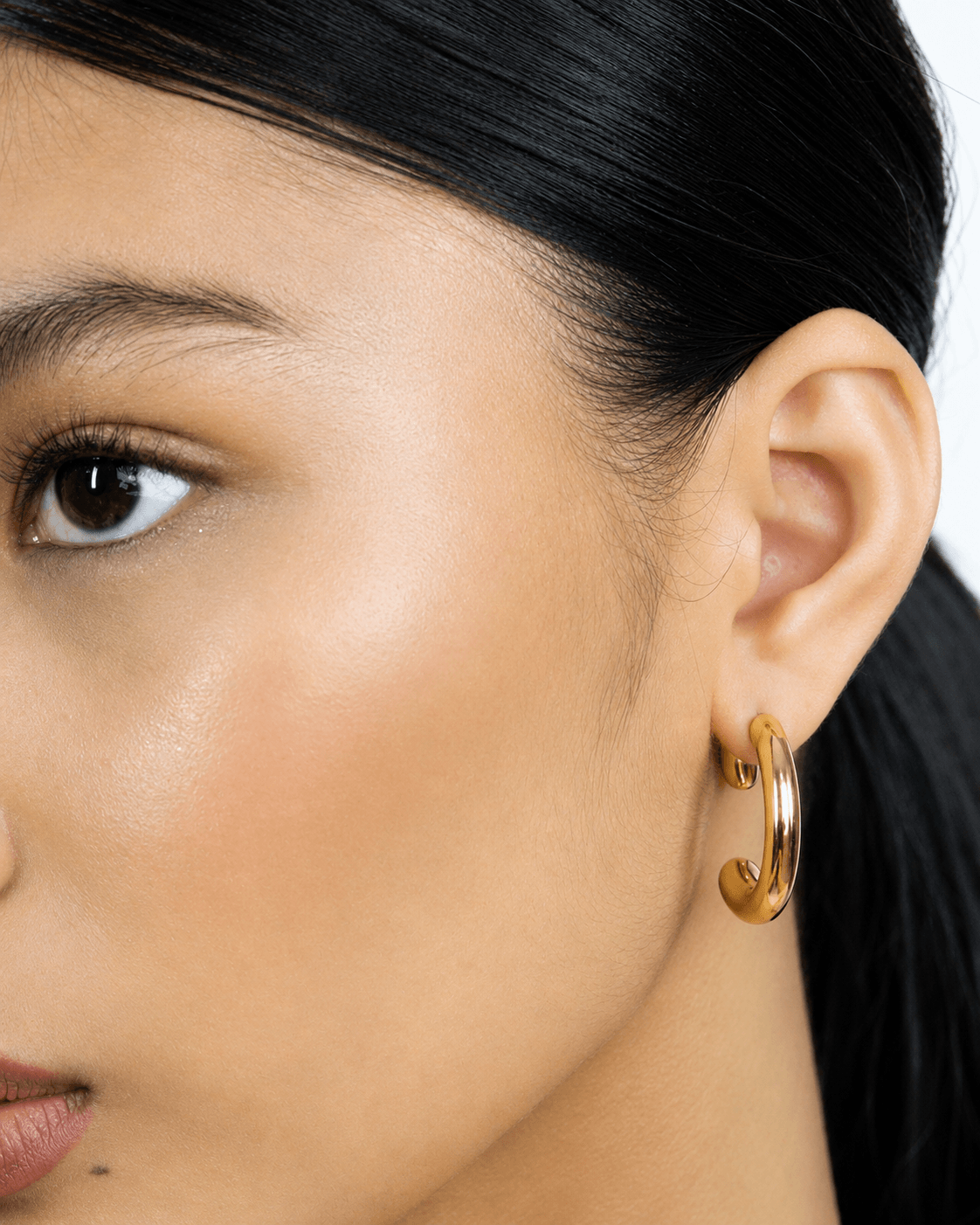 Two tone gold and silver 360 front back hoop earrings displayed on a soft neutral background. Modern sculptural shape hoop earrings with chunky curved silhouette, minimalist statement jewelry designed for contemporary everyday wear.