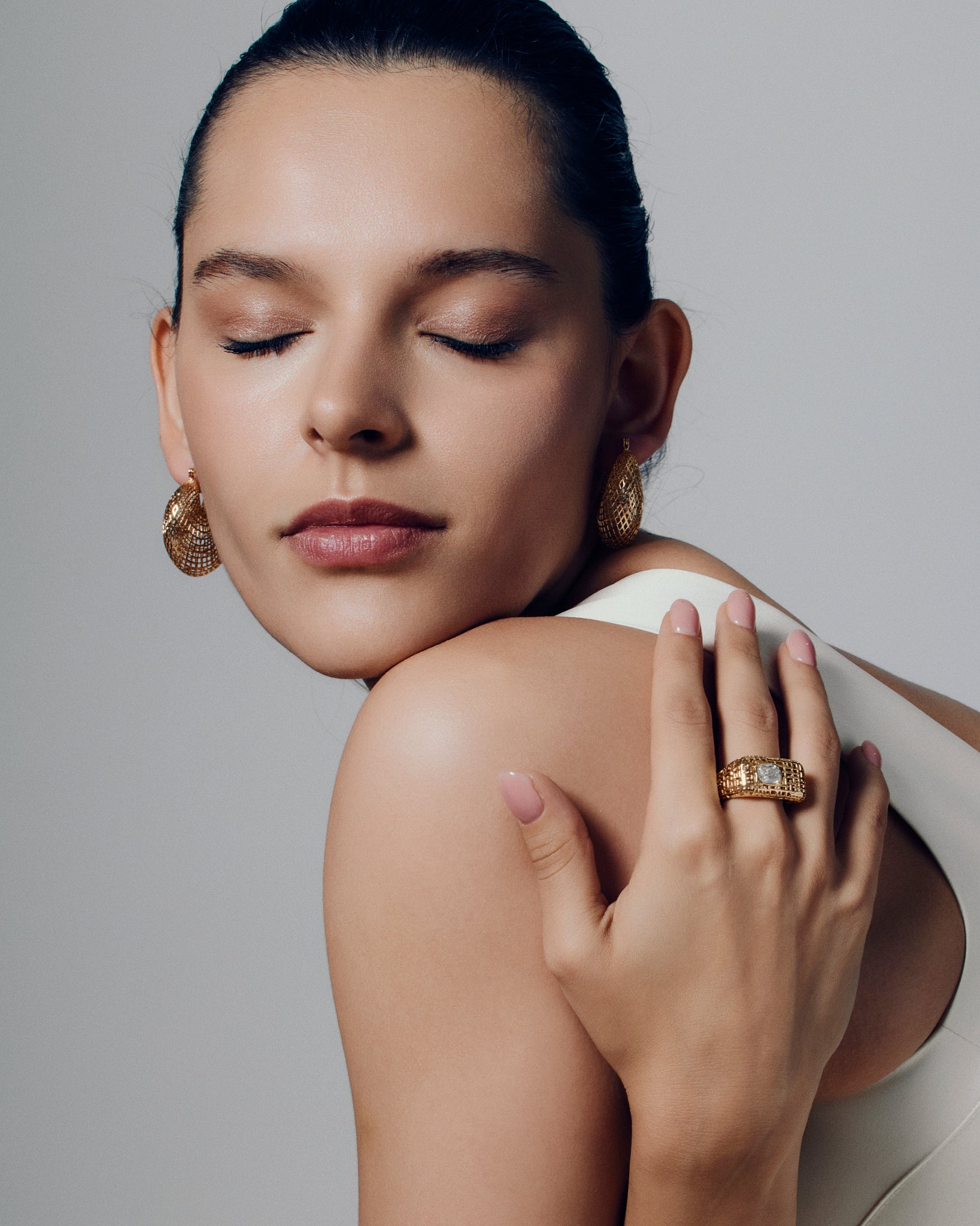 Model wearing open work square gold ring with clear stone, showing the chunky sculptural texture and modern grid-pattern design. A bold gold statement ring that elevates everyday style or evening wear, highlighting its geometric shape and luxurious finish for a refined yet artistic look.