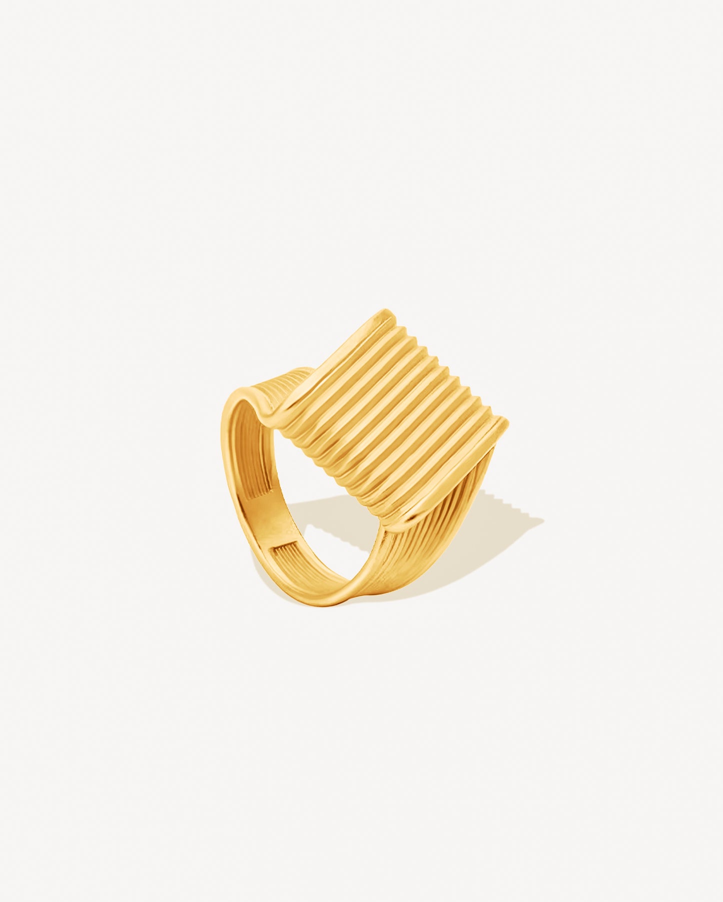 gold chunky ring with ribbed design on a white background