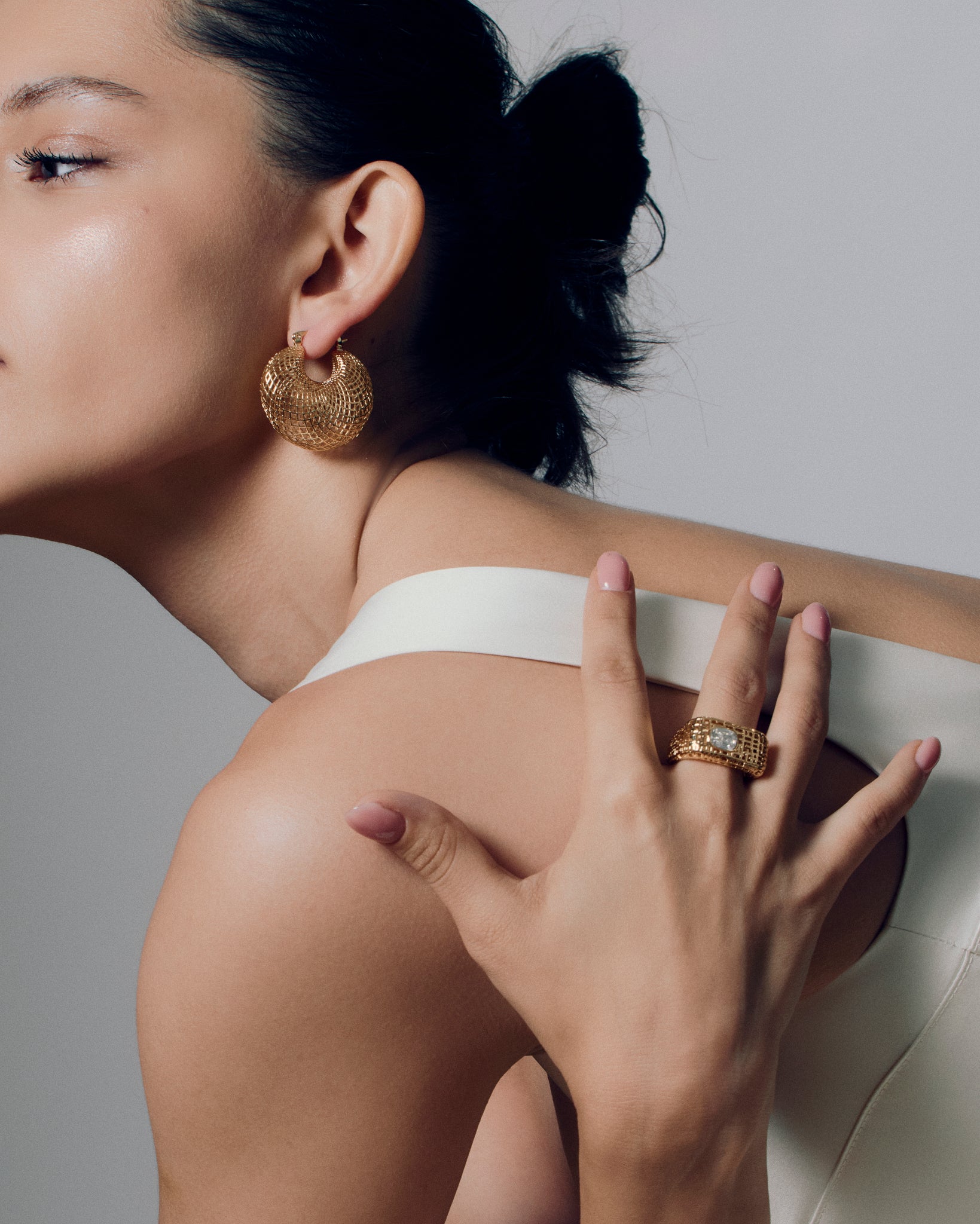 Model wearing open work square gold ring with clear stone, showing the chunky sculptural texture and modern grid-pattern design. A bold gold statement ring that elevates everyday style or evening wear, highlighting its geometric shape and luxurious finish for a refined yet artistic look.
