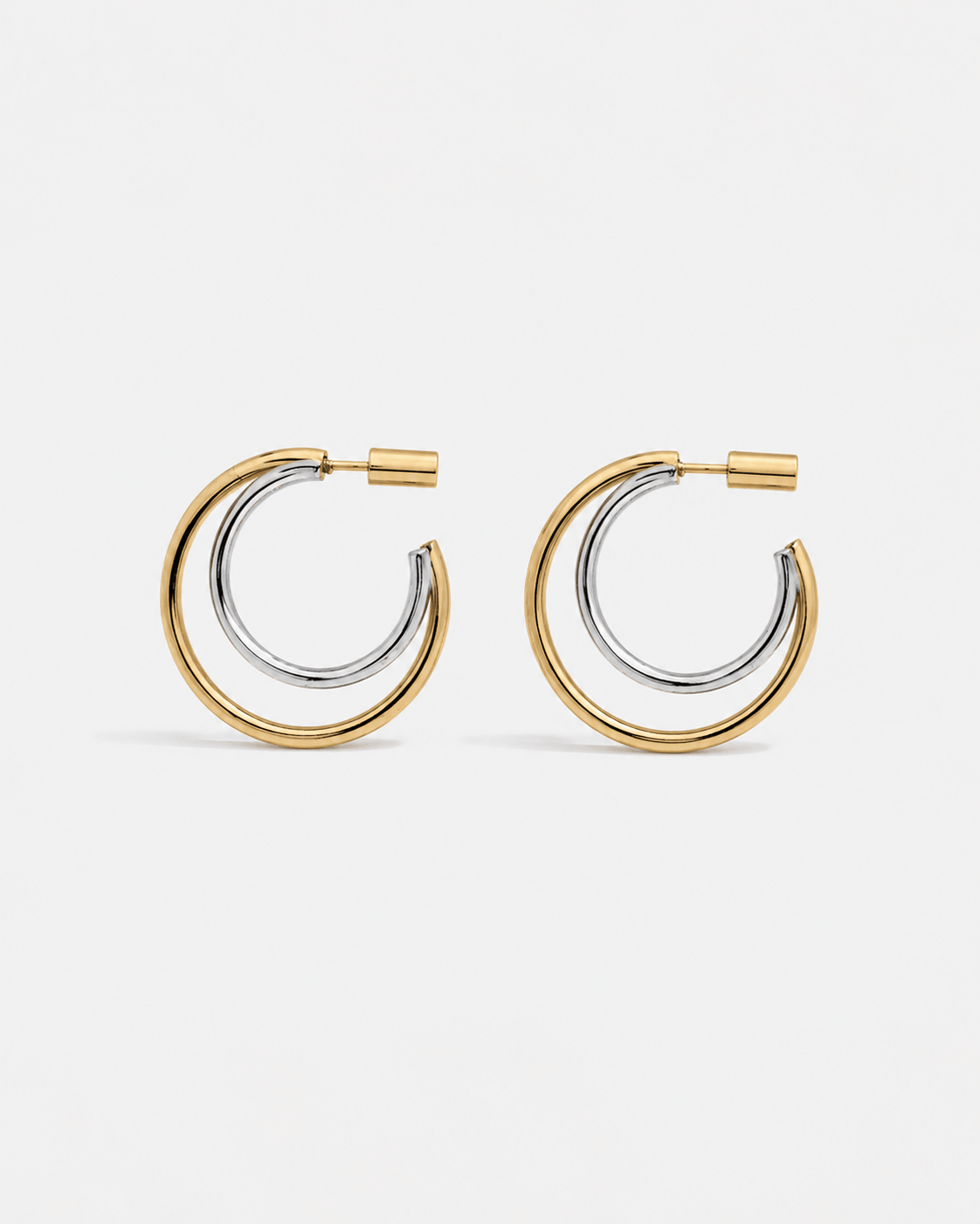 Modern two tone double hoop earrings featuring a polished gold outer hoop and silver inner hoop with secure tube lock closure, minimalist mixed metal statement earrings for everyday wear and modern jewelry styling.