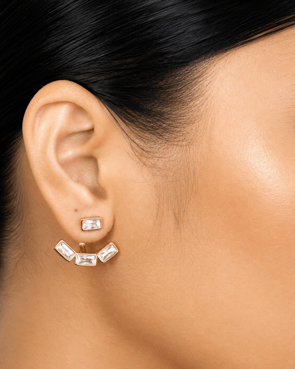 Detachable baguette zircon ear jacket earrings in gold finish displayed on a soft neutral background. Modern geometric stud earrings with removable ear jacket design, featuring sparkling rectangular CZ stones and minimalist contemporary styling for everyday wear and statement looks.